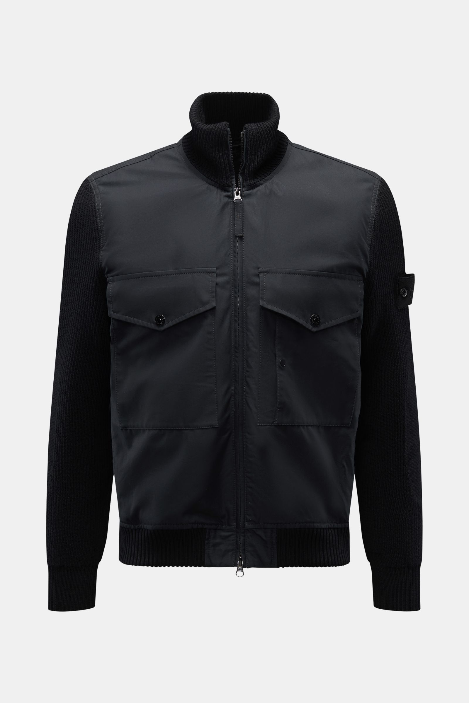 Front view of Stone Island Blouson 'Ghost Piece' schwarz, a cool monochrome hybrid jacket with cotton corpus, wool knit sleeves, slim fit, two-way zipper, high collar, flap pockets, tonal badge on upper arm, and flexible ribbed cuffs.