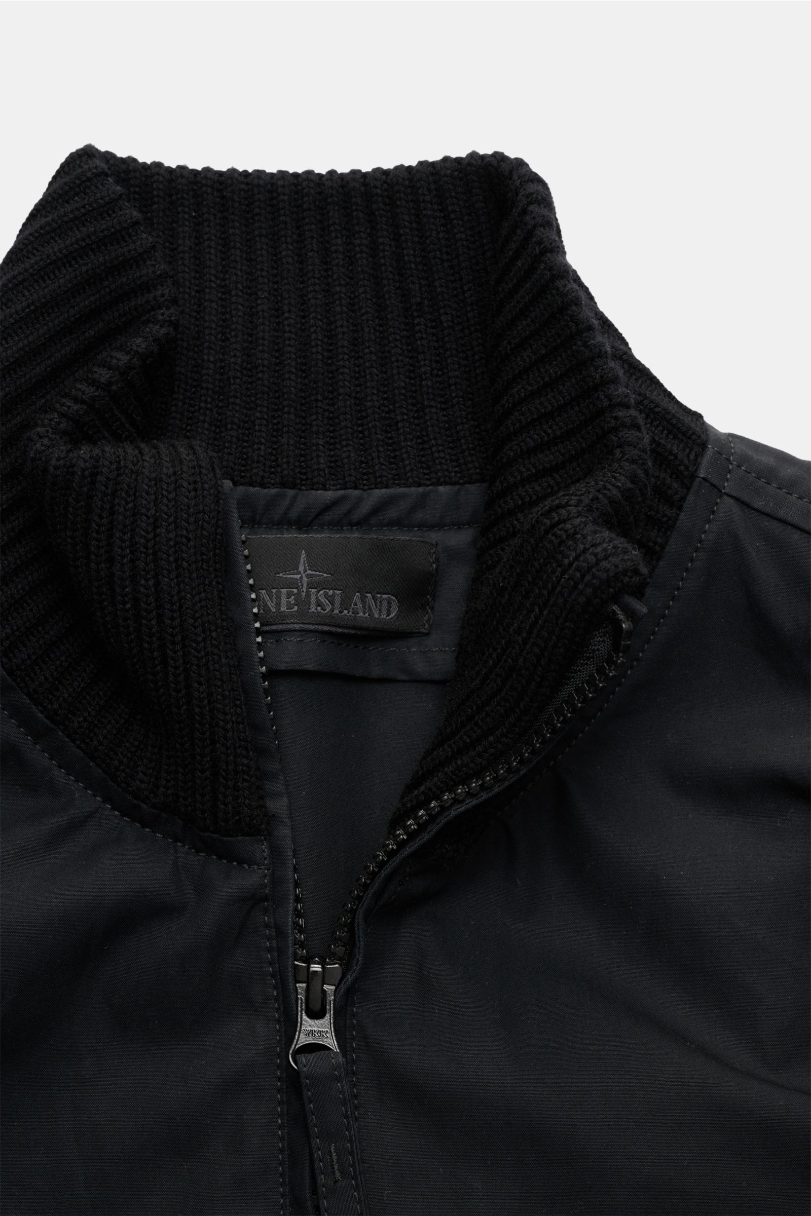 Nahaufnahme des hoch geschlossenen Kragens und Zwei-Wege-Reißverschlusses des schwarzen Stone Island Blouson 'Ghost Piece' aus Baumwolle und Wolle mit weichem Griff.