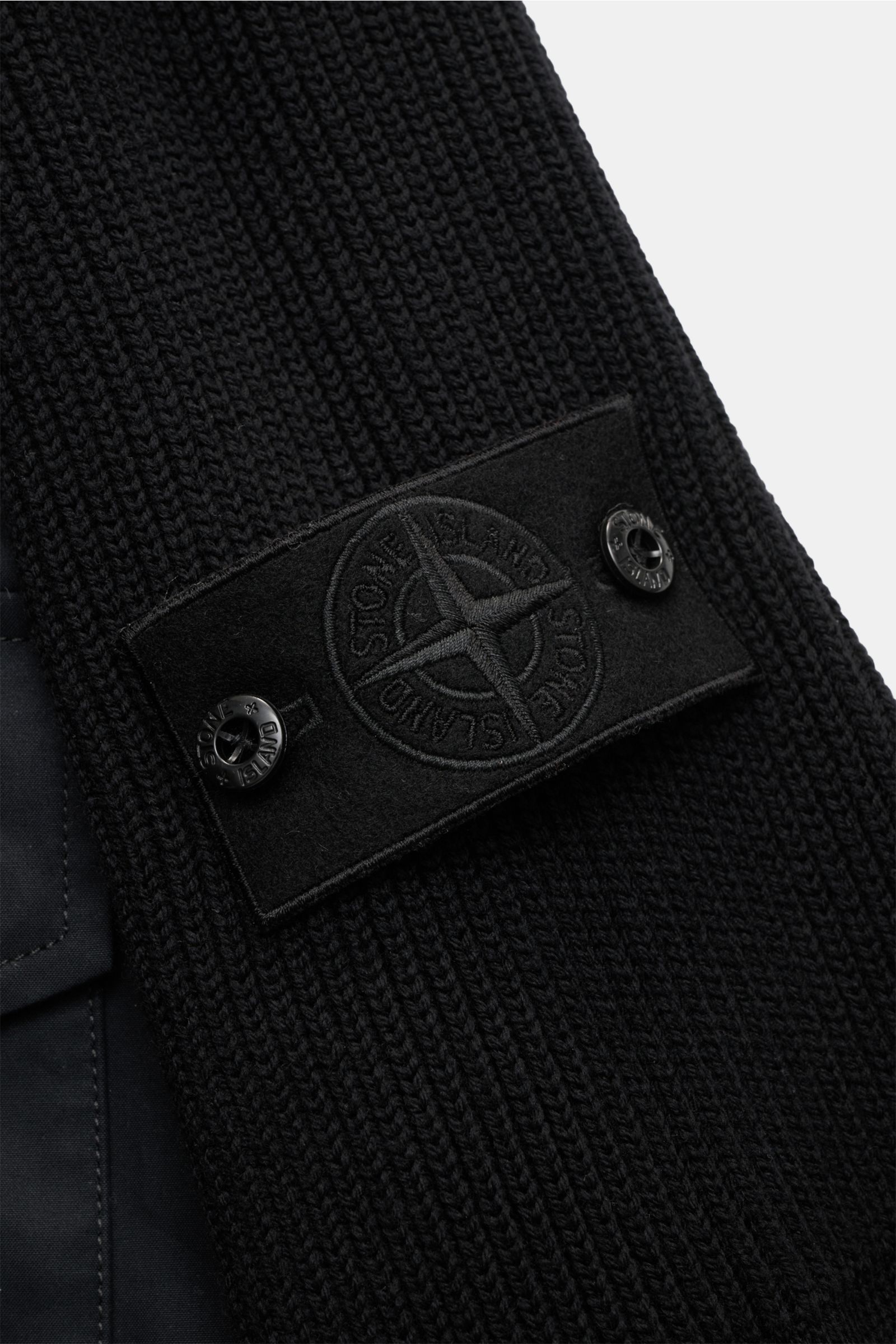 Nahaufnahme des tonalen Stone Island Blouson 'Ghost Piece' schwarz Ärmels mit Strickelementen, Badge, weichem Griff, Slim Fit und Rippbündchen.