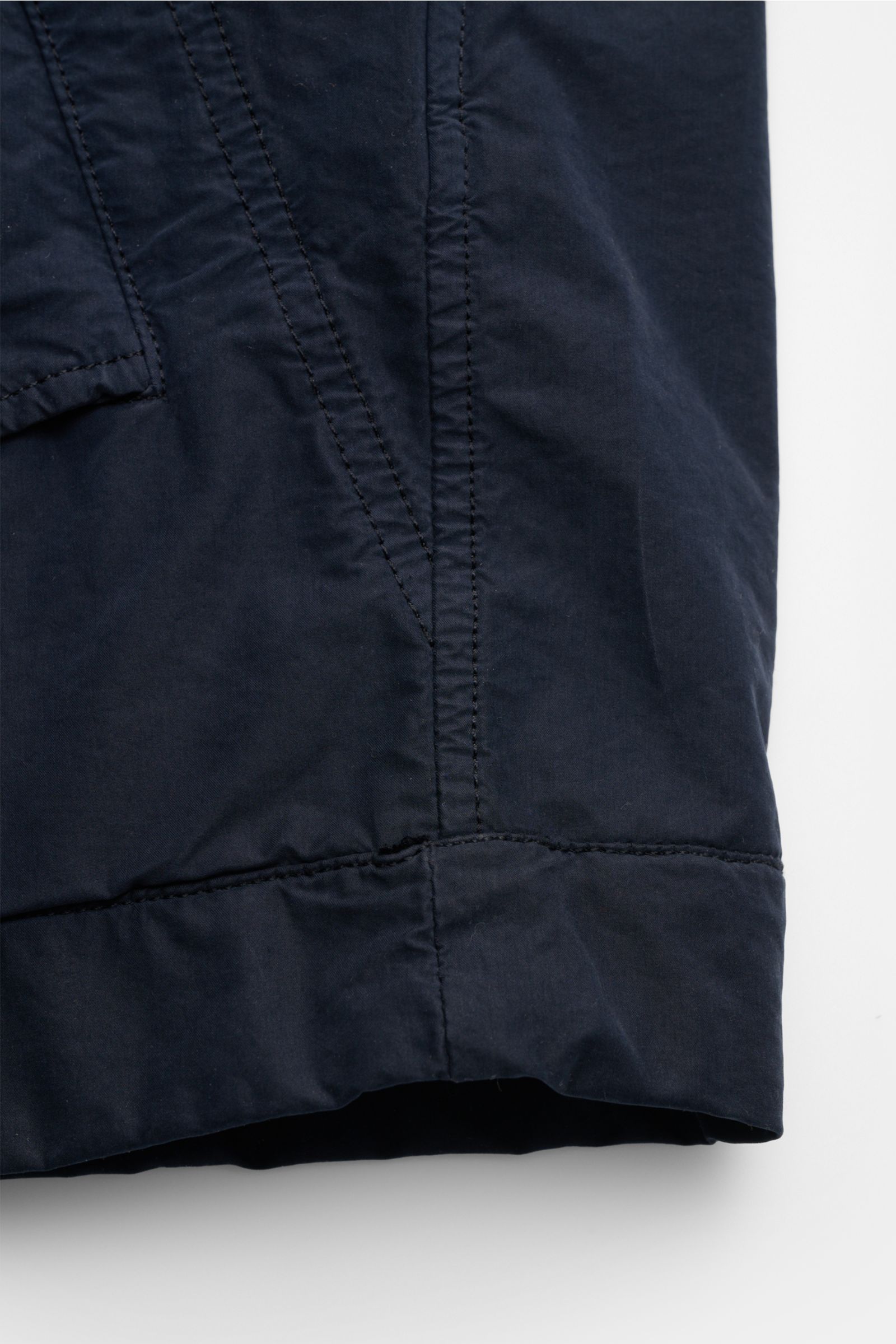 Close-up view of the hem and side seam of the Stone Island Jacke 'Ghost Piece' navy, showcasing navy microfaser fabric with detailed stitching. Urbanes Essential: Die STONE ISLAND Jacke aus der 'Ghost Collection' überzeugt mit legerem Design und hochwerti
