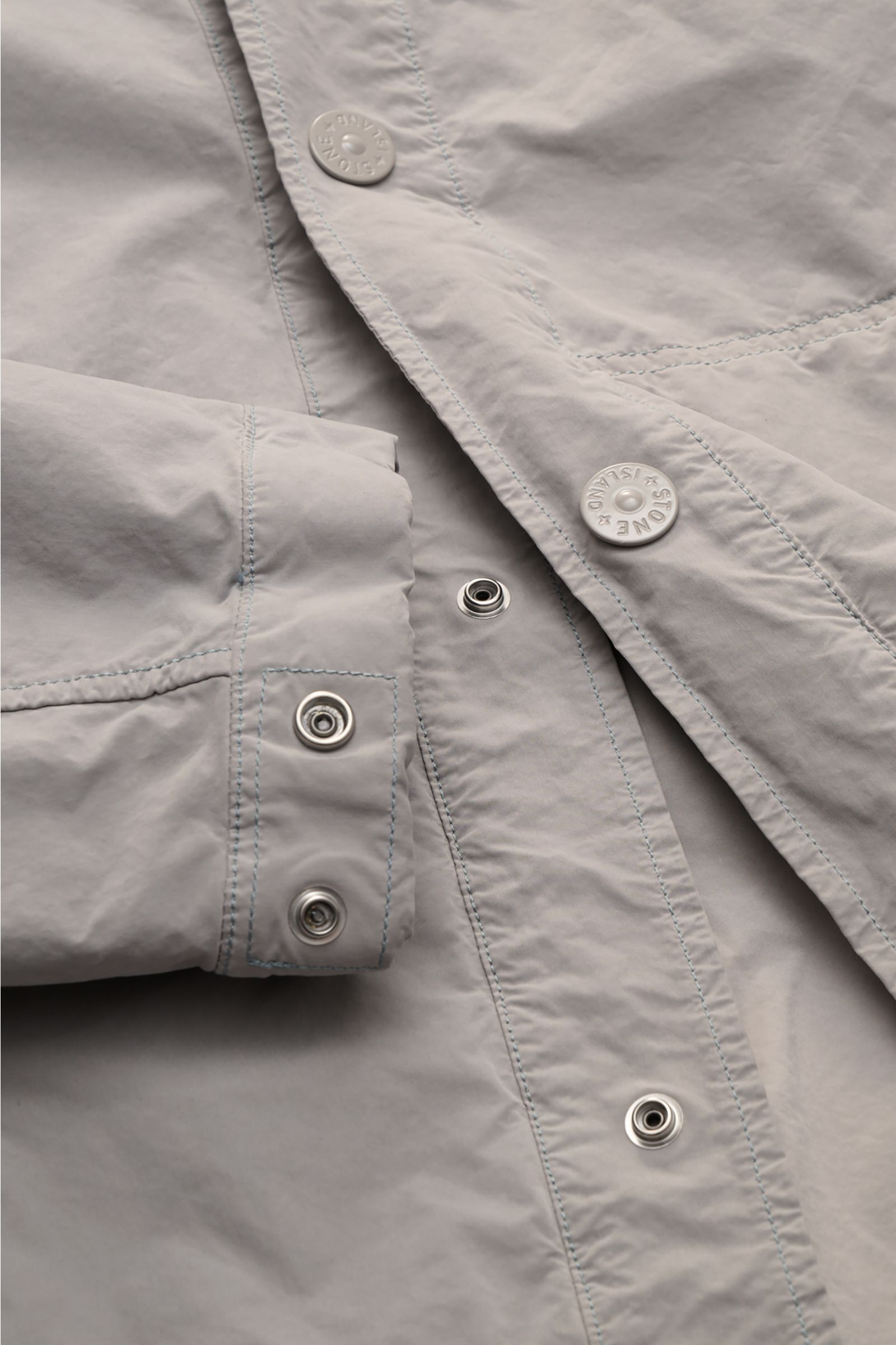 Close-up front view of Stone Island Jacket 'Ghost Piece' light grey showing snap button placket, cuffs, and microfibre fabric details.

Description: Urban essential: This STONE ISLAND jacket from the 'Ghost Collection' impresses with its casual design 