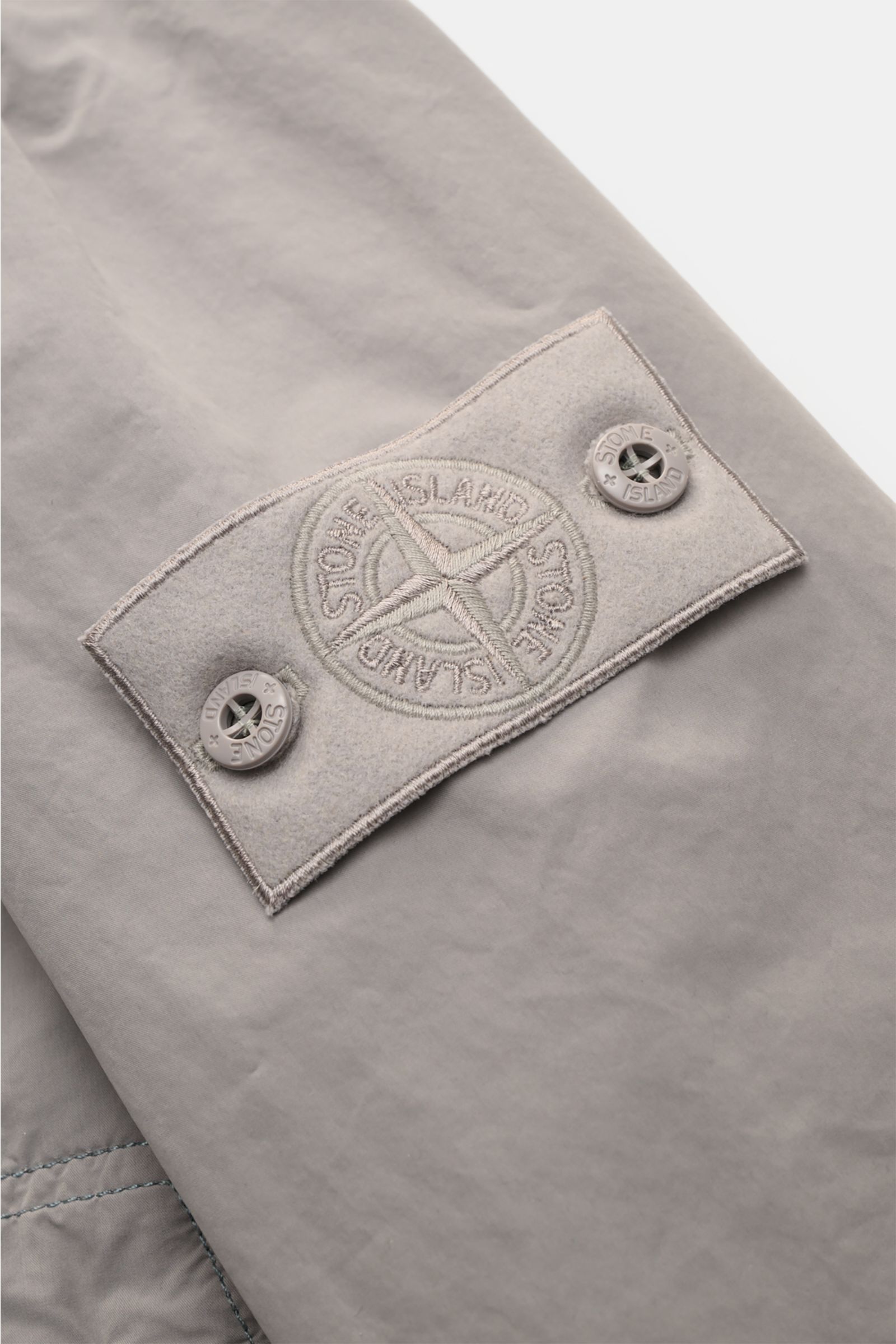 Close-up of the tonal compass badge on the upper sleeve of the Stone Island Jacket 'Ghost Piece' light grey, showing high-quality microfibre fabric.

Description: Urban essential: This STONE ISLAND jacket from the 'Ghost Collection' impresses with its 