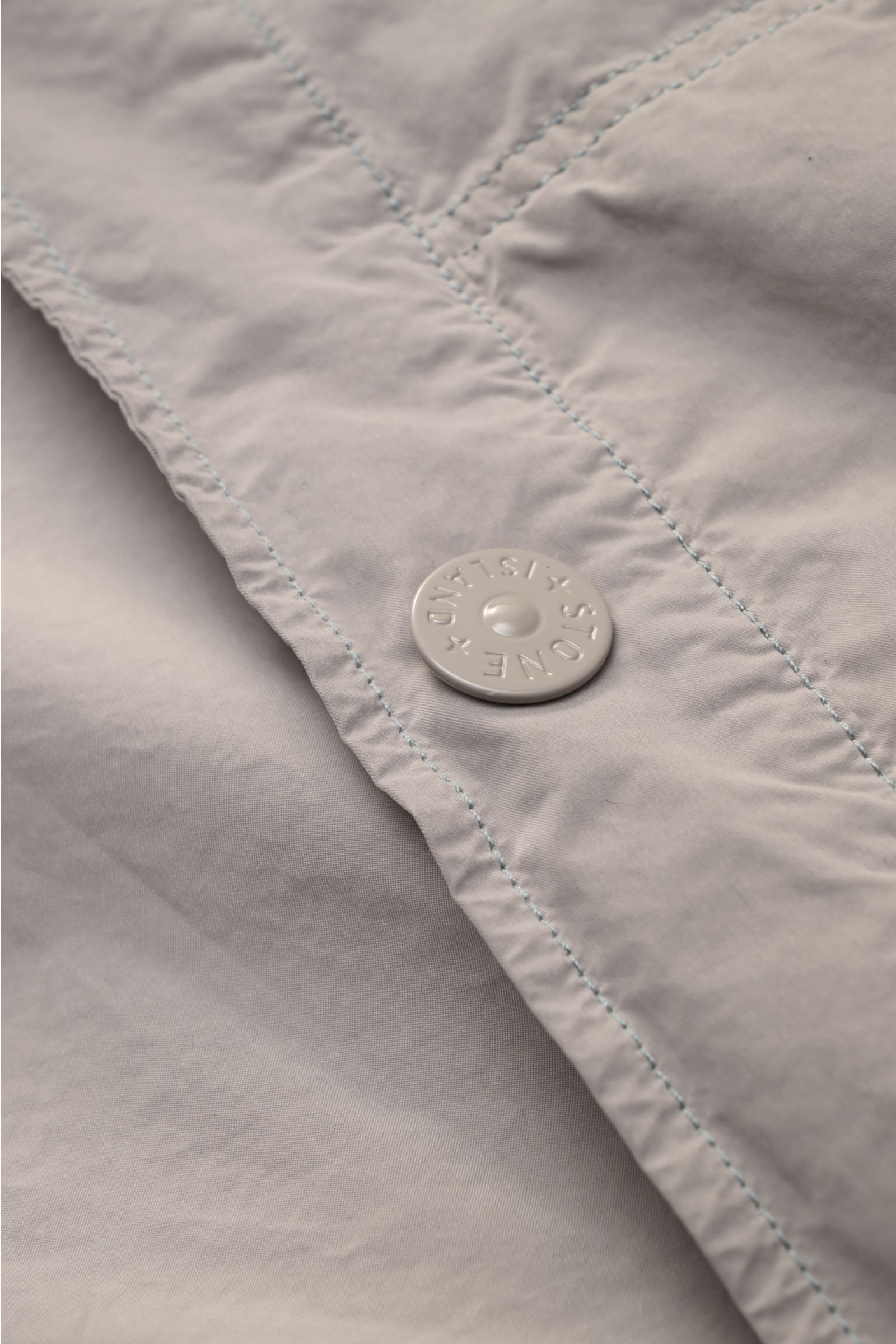 Close-up detail of the snap button and stitching on the Stone Island Jacket 'Ghost Piece' light grey, photographed from above.

Urban essential: This STONE ISLAND jacket from the 'Ghost Collection' impresses with its casual design and high-quality micr