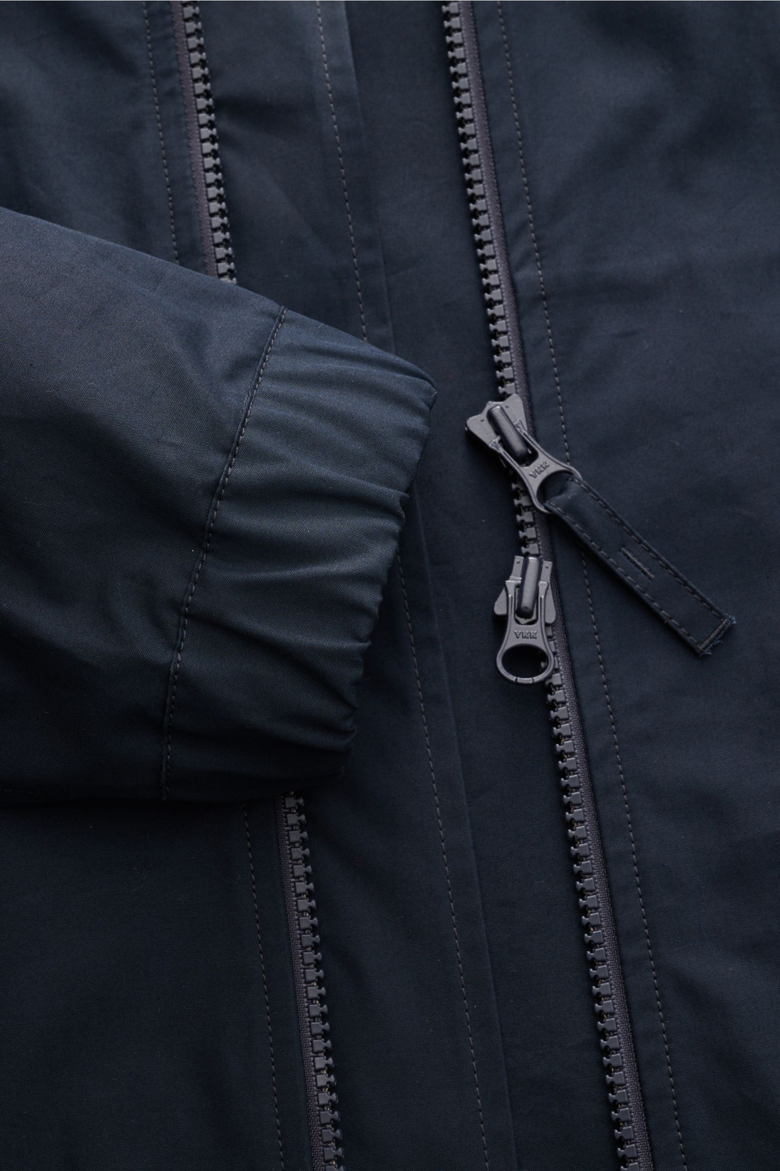 Close-up front view of the Stone Island Jacke 'All-Weather S.I. Ghost Piece' navy, showing the robust two-way zipper and cuff with button, made of pure cotton canvas with a smooth touch, wind- and water-repellent, slim fit, practical hood, front flap pock