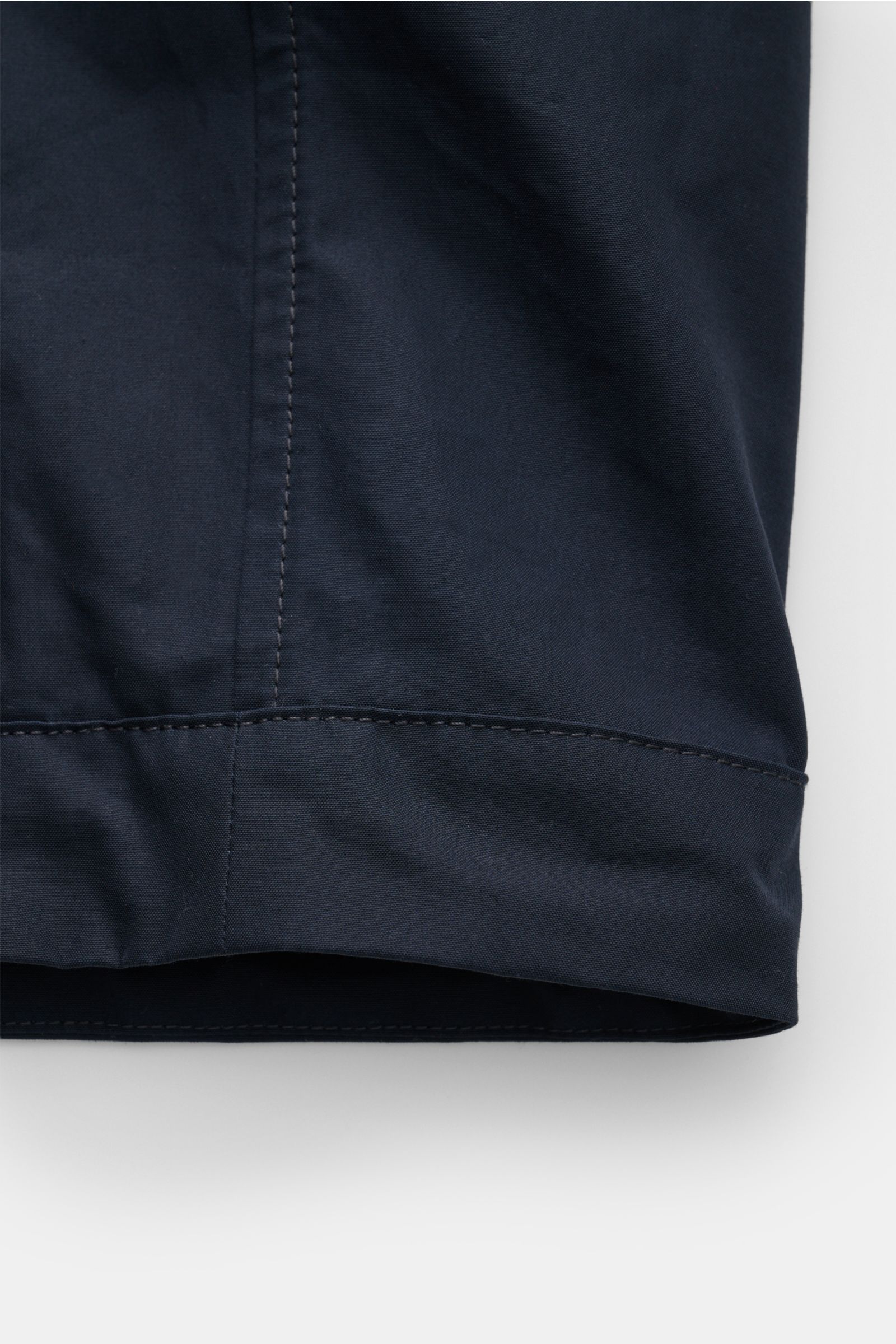 Close-up front view of the hem detail of the Stone Island Jacke 'All-Weather S.I. Ghost Piece' navy, made from pure cotton canvas with smooth grip, wind- and water-resistant, featuring adjustable hem width. Funktion trifft Komfort: Die STONE ISLAND Jacke 