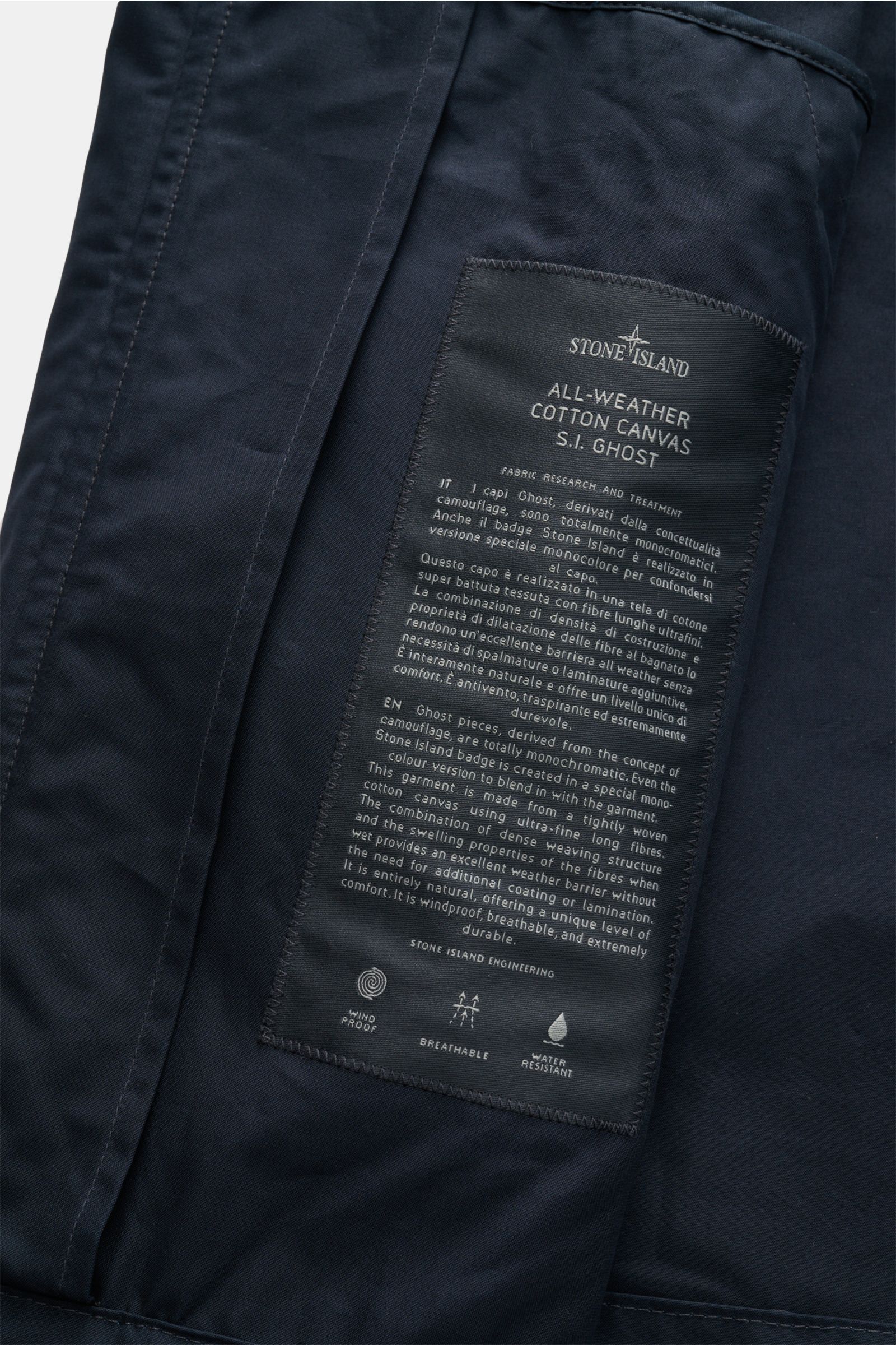 Close-up inside view of Stone Island Jacke 'All-Weather S.I. Ghost Piece' navy showing detailed fabric label, cotton canvas, and stitching.

Description to include: 
Funktion trifft Komfort: Die STONE ISLAND Jacke aus der 'Ghost' Capsule wurde aus einem B