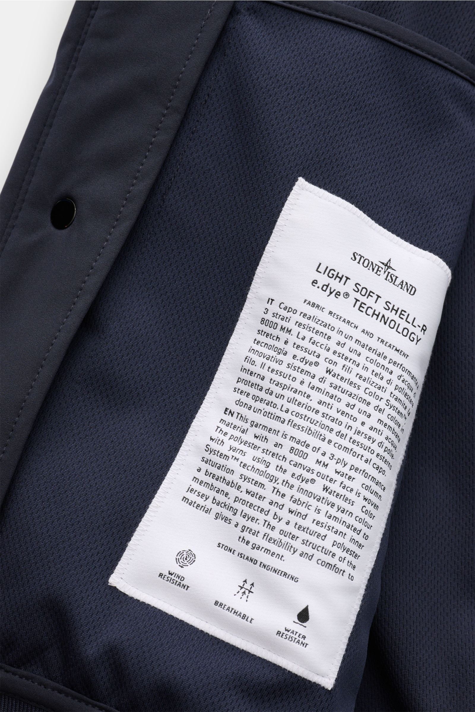 Nahaufnahme des inneren Mesh-Futterstoffs mit weißem Label des Stone Island Blouson 'Light Soft Shell-R' navy, wind- und wasserabweisend, Slim Fit, mit Zipper-Fronttaschen und elastischen Bündchen.