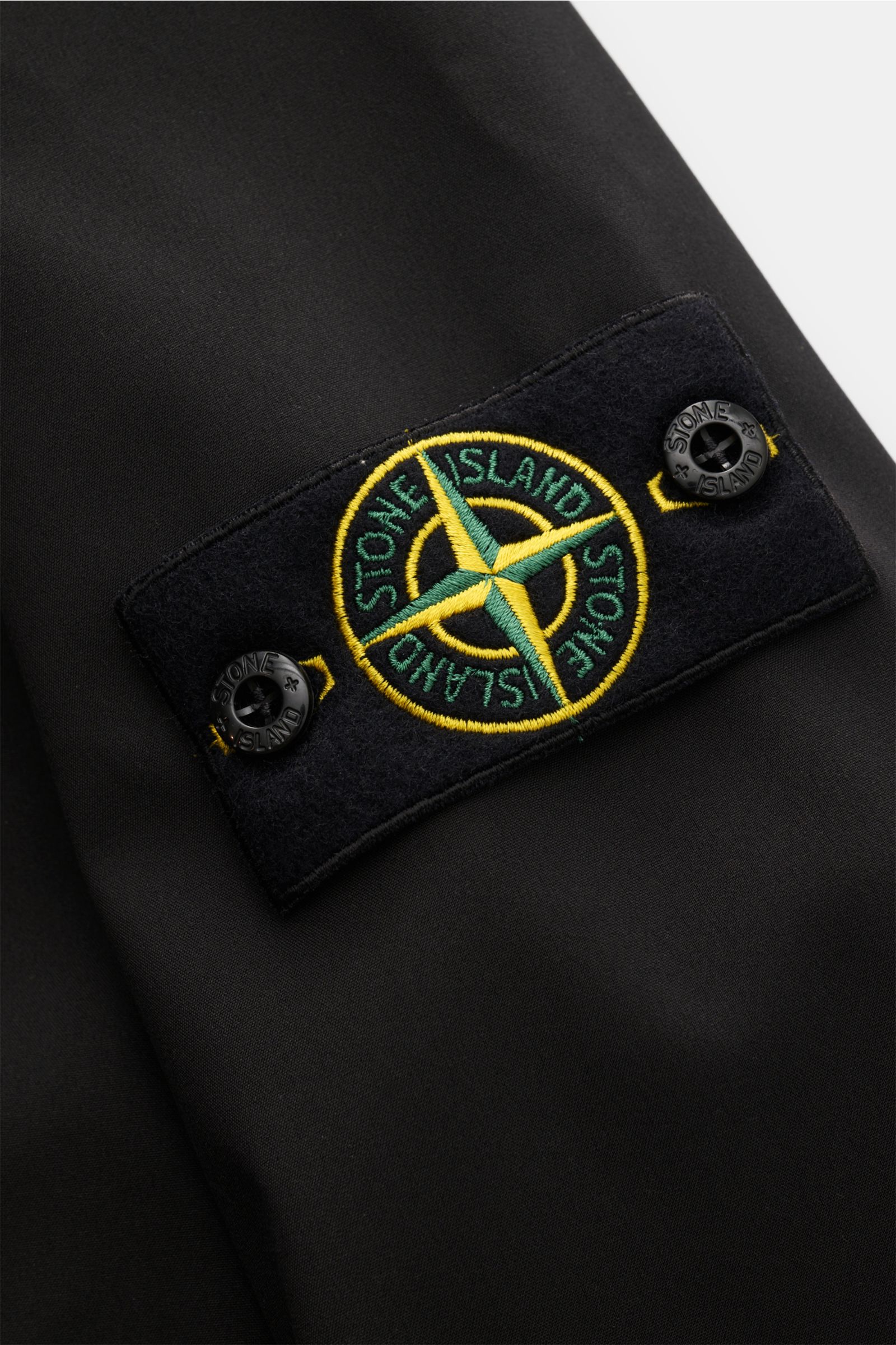 Stone Island Blouson 'Light Soft Shell-R' schwarz, Detailaufnahme der hochwertigen Microfaser mit Kompass-Badge am Ärmel, wind- und wasserabweisend.