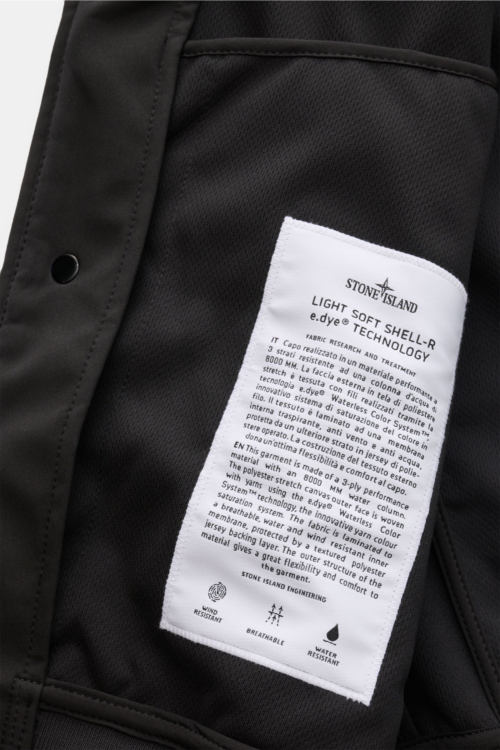 Nahaufnahme des Innenfutters vom Stone Island Blouson 'Light Soft Shell-R' schwarz mit weißem Label und Mesh-Futterstoff.
