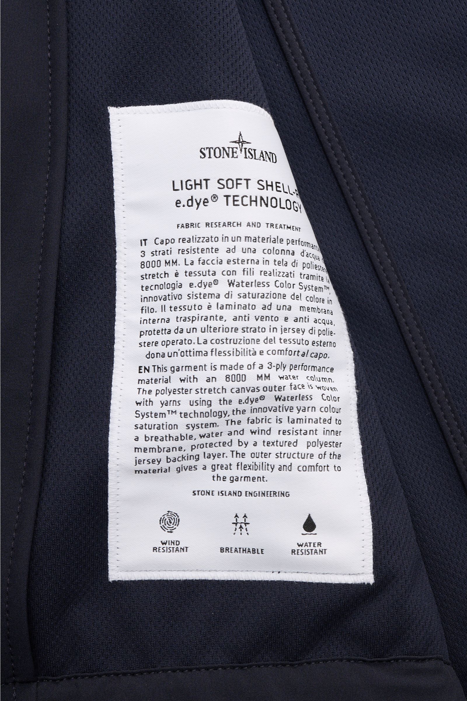 Alt-Tag (124 Zeichen): Nahaufnahme des Innenteils der Stone Island Jacke 'Light Soft Shell-R' navy mit weißem Pflegeetikett und Softshell-Material.