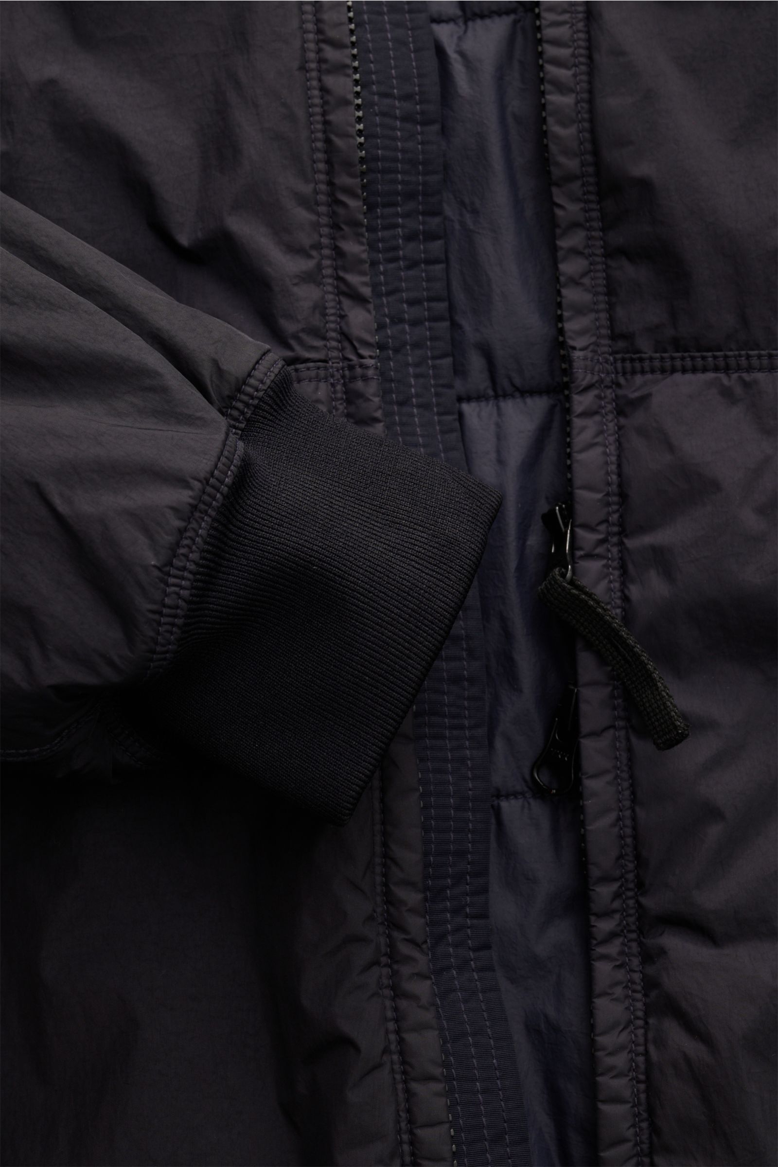 Close-up front view of Stone Island Jacke 'Garment Dyed Crinkle Reps NY' dark navy showing ribbed elastic sleeve cuff, two-way zipper, finely stitched lightweight microfibre fabric with resin coating for crinkle effect. Funktion trifft Style: Die sportive
