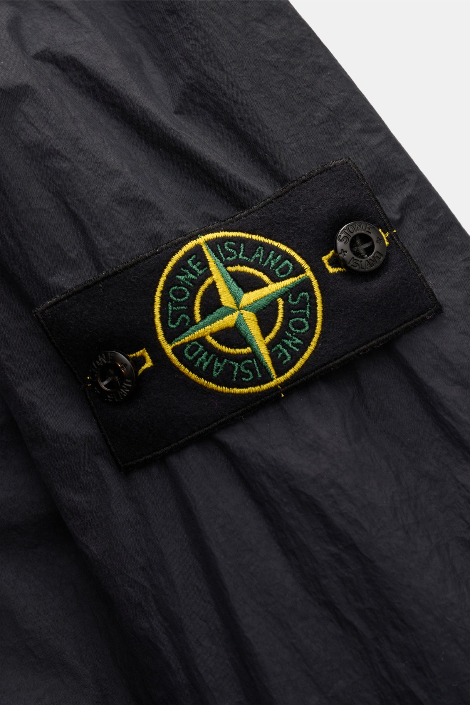 Nahaufnahme der Stone Island Jacke 'Garment Dyed Crincle Reps NY' dark navy, zeigt das Kompass-Badge auf technischem, wasserabweisendem und windblockendem Material.