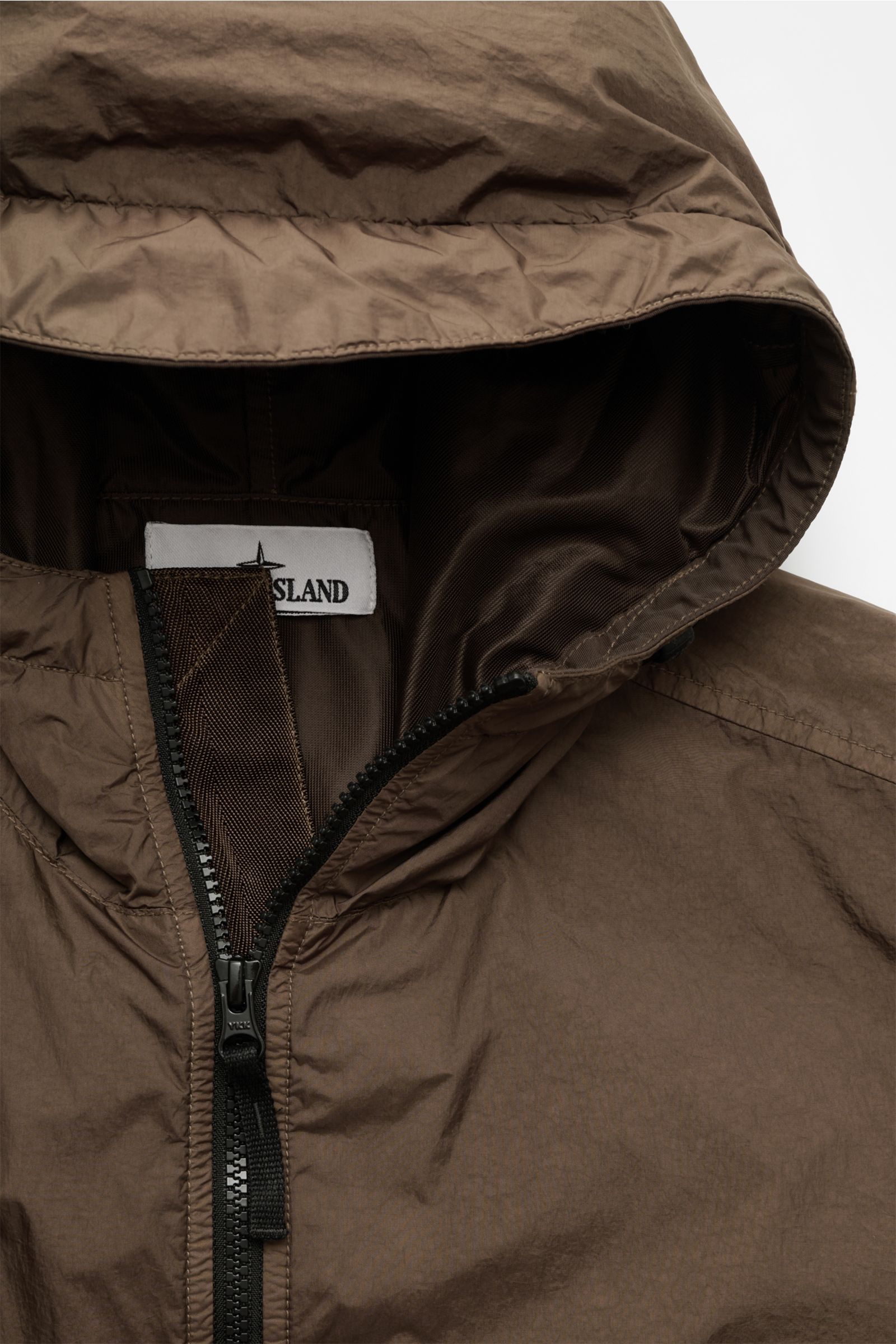 Nahaufnahme der Stone Island Jacke 'Garment Dyed Crincle Reps NY' braun mit Kapuze und robustem Reißverschluss, technische Microfaser, wasserabweisend, windblockend, Slim Fit, glänzendes Futter, Ärmel- und Saumregulierung sichtbar.