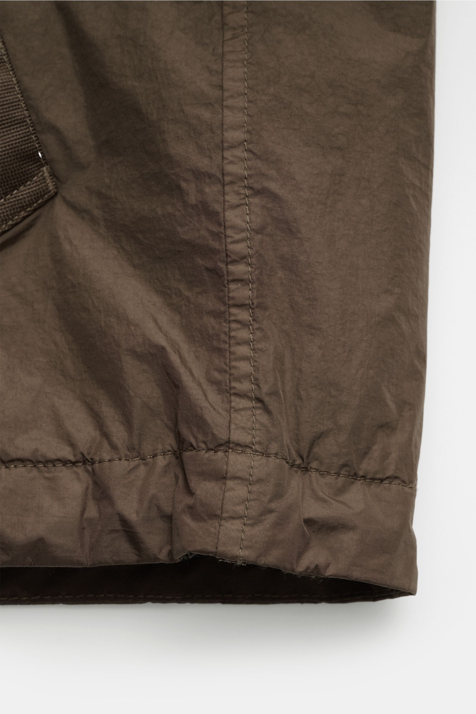 Nahaufnahme der Stone Island Jacke 'Garment Dyed Crincle Reps NY' braun am unteren Saum, technische Microfaser, wasserabweisend, windblockend, Slim Fit.