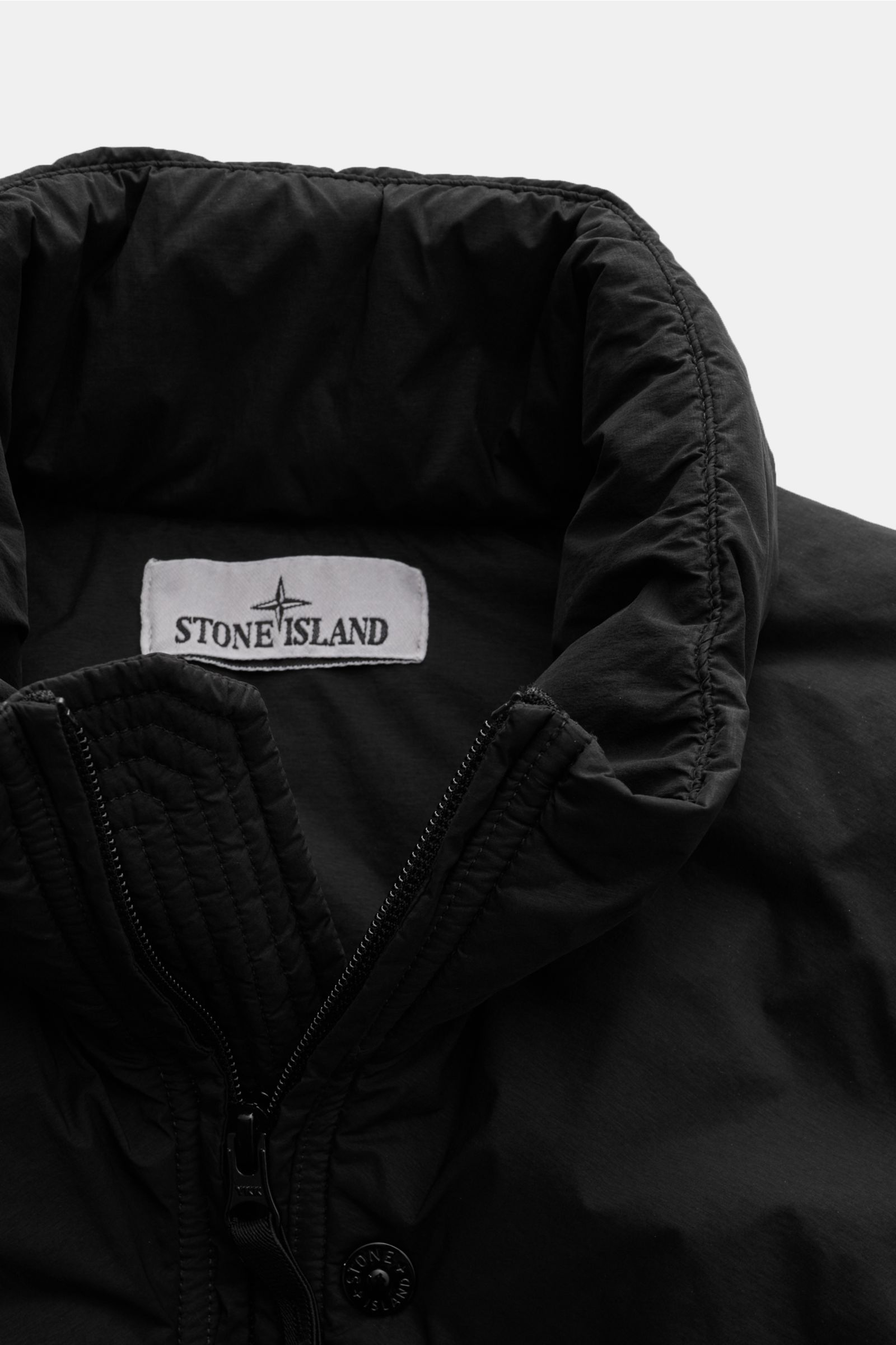 Stone Island Daunenjacke 'Seamless Tunnel Nylon Down-TC' schwarz, Nahaufnahme von oben, hoher Stehkragen, wasserabweisend, leichte Daunenfüllung.