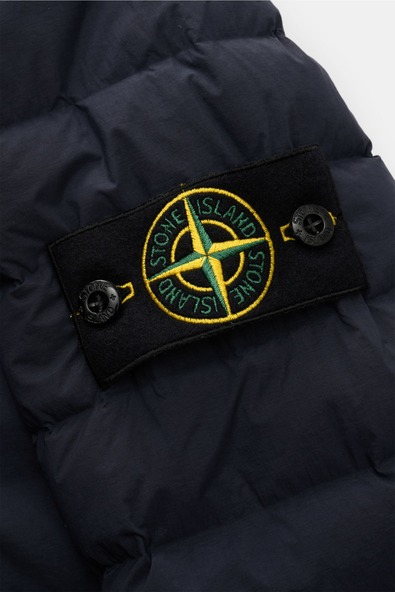 Stone Island Daunenjacke 'Seamless Tunnel Nylon Down-TC' dark navy, Detailansicht des typischen Kompass-Badges auf hochwertiger, wasserabweisender Microfaser mit leichter Daunenfüllung.
