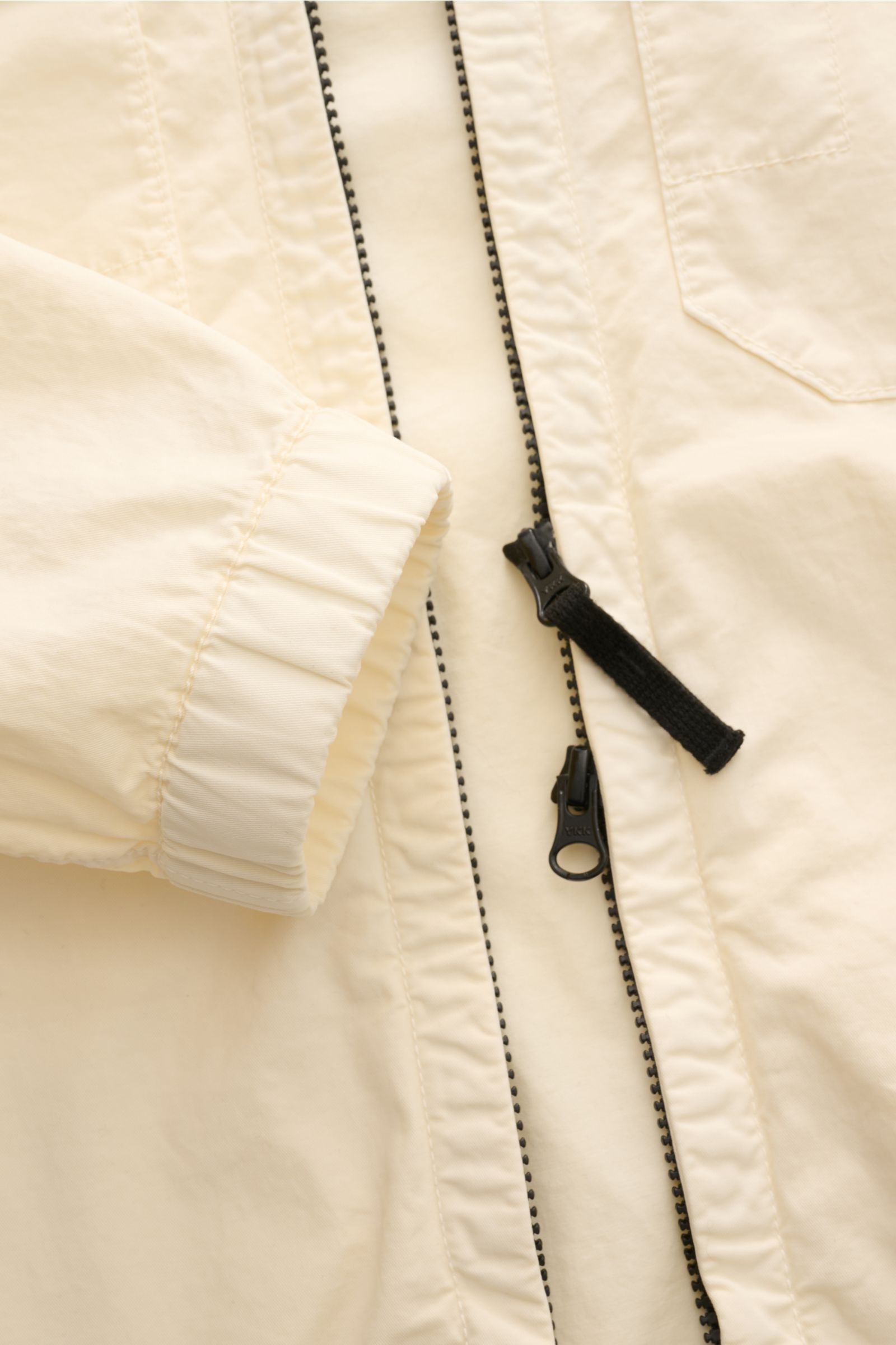 Stone Island Blouson 'Stretch Cotton Twill-TC' creme, sportiv, slim fit, elastische Baumwolle, elastische Bündchen, Zwei-Wege-Reißverschluss, Front- und Brusttaschen, Kapuze mit Tunnelzug, Detailfoto von vorne oben.