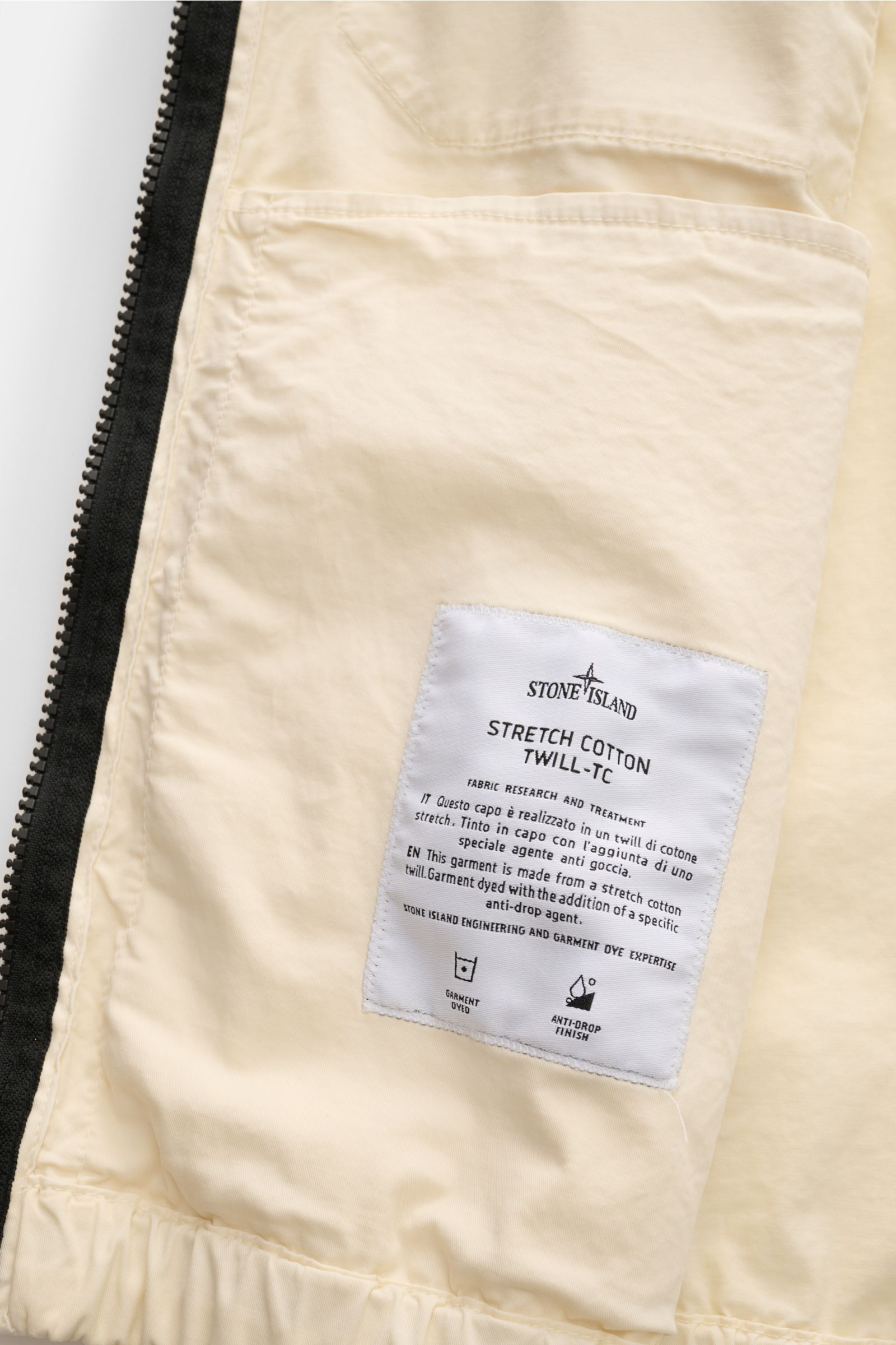 Nahaufnahme des inneren Taschenbereichs des Stone Island Blouson 'Stretch Cotton Twill-TC' creme mit elastischem Saum und robustem Reißverschluss.