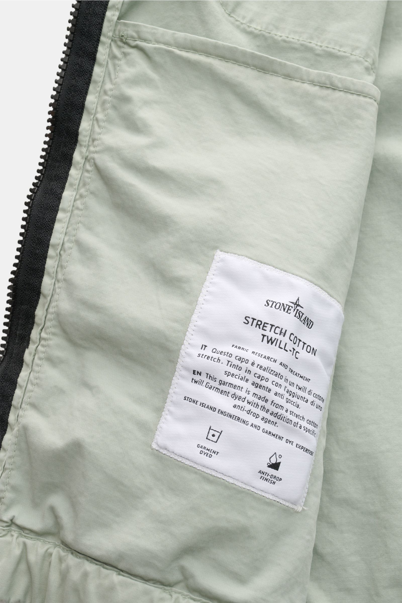 Innenansicht des Stone Island Blouson 'Stretch Cotton Twill-TC' salbei mit elastischer Baumwolle, Label und robustem Reißverschluss.