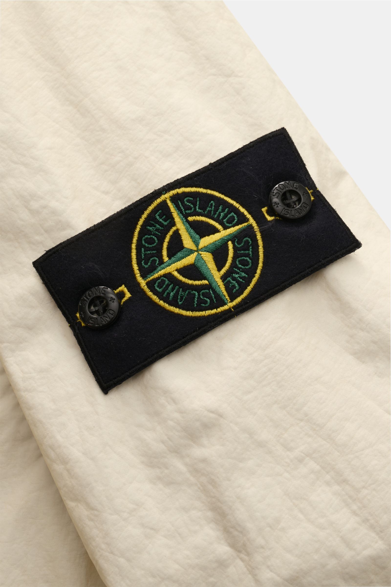 Alt-Tag (124 Zeichen): Nahaufnahme der cremefarbenen Stone Island Jacke 'Membrana' mit Kompass-Badge aus hochwertiger Microfaser, wasserabweisend.