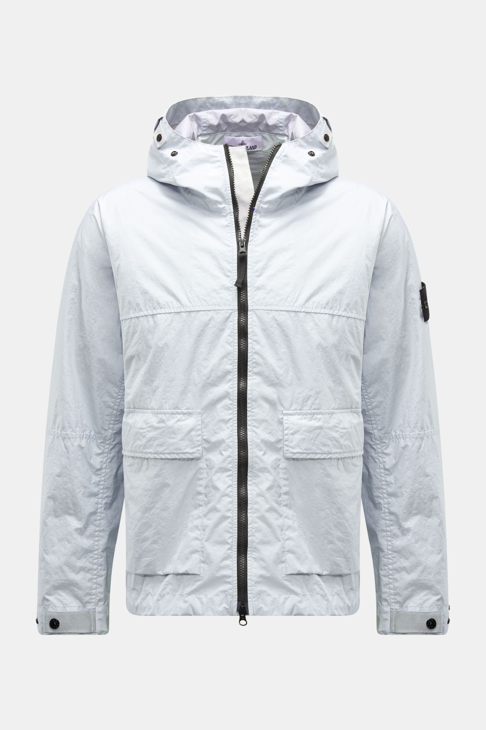 Front view of Stone Island Jacke 'Membrana' hellgrau, a light grey, wind- and water-resistant jacket with hood, two-way zipper, flap pockets, button cuffs, and compass badge on sleeve.