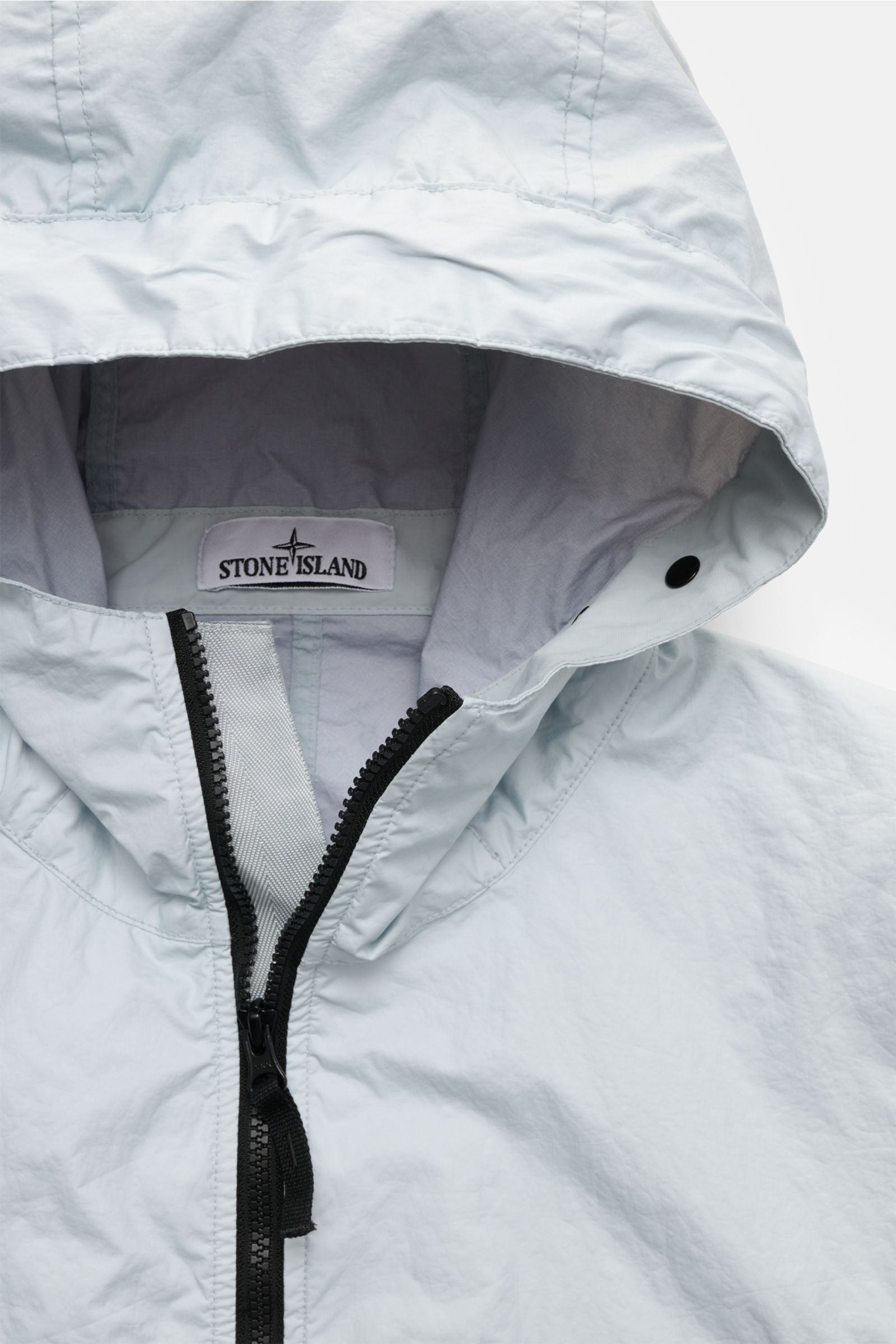 Close-up front view of the Stone Island Jacke 'Membrana' hellgrau, showing its light grey hood with black zipper, made of high-quality microfiber, wind- and water-repellent with breathable membrane, featuring a regular fit and two-way zipper.