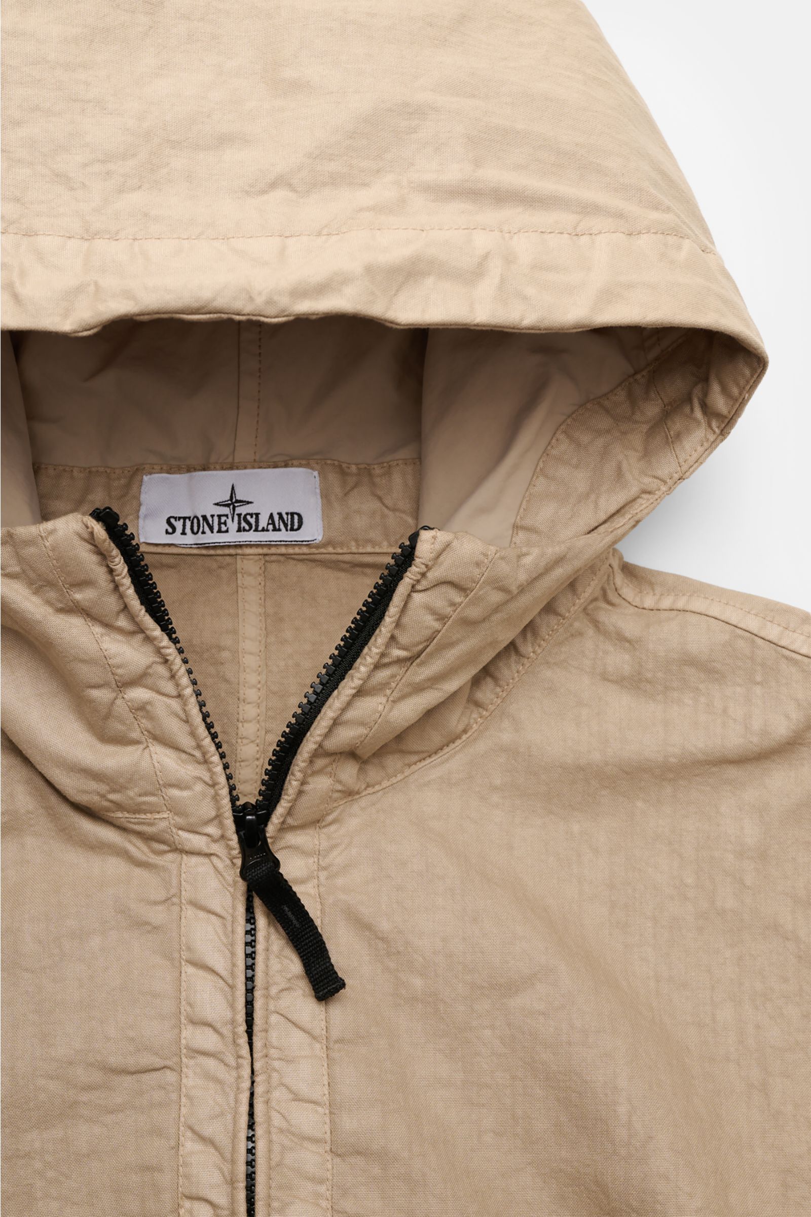 Stone Island Jacke 'Organic-Look Nylon Panama-TC' beige shown from a close-up top-front view, highlighting hood, black two-way zipper, and textured microfiber canvas. Mit der Jacke 'Organic-Look Nylon Panama-TC' präsentiert STONE ISLAND ein modernes Mo