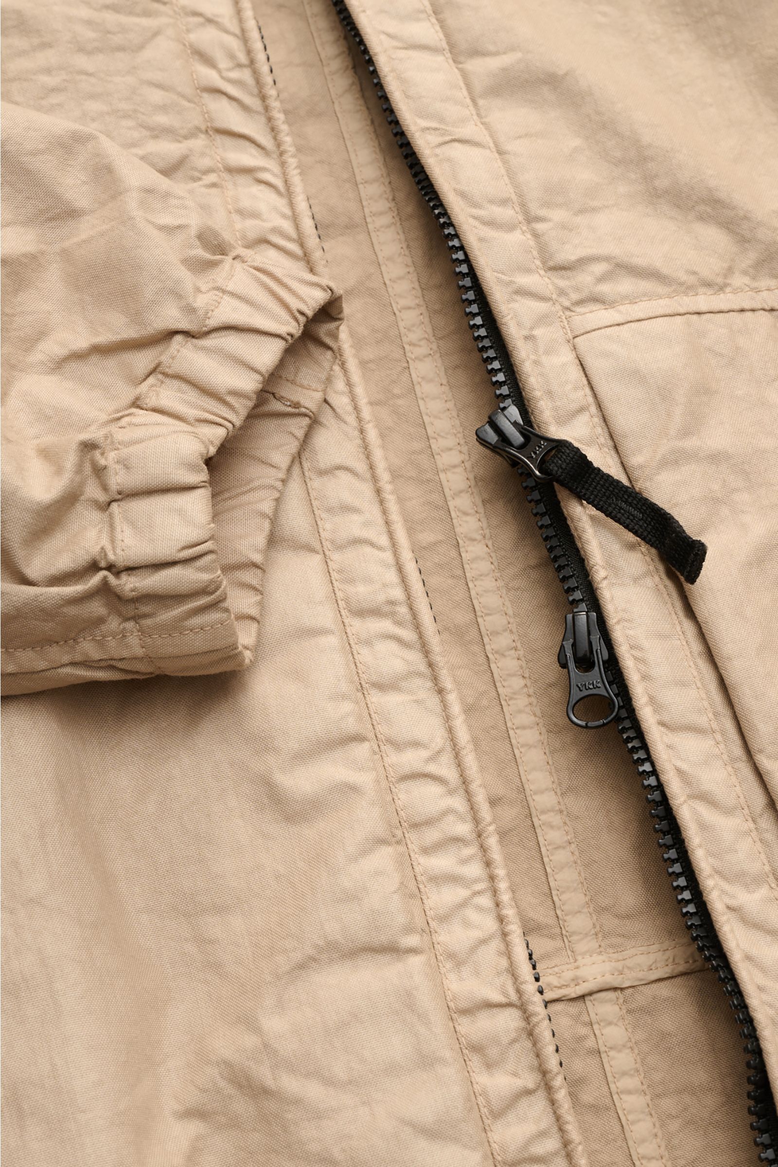 Close-up front view of Stone Island Jacke 'Organic-Look Nylon Panama-TC' beige showing zipper and elastic cuff details.

Mit der Jacke 'Organic-Look Nylon Panama-TC' präsentiert STONE ISLAND ein modernes Modell aus dicht gewebtem Microfaser-Canvas mit 