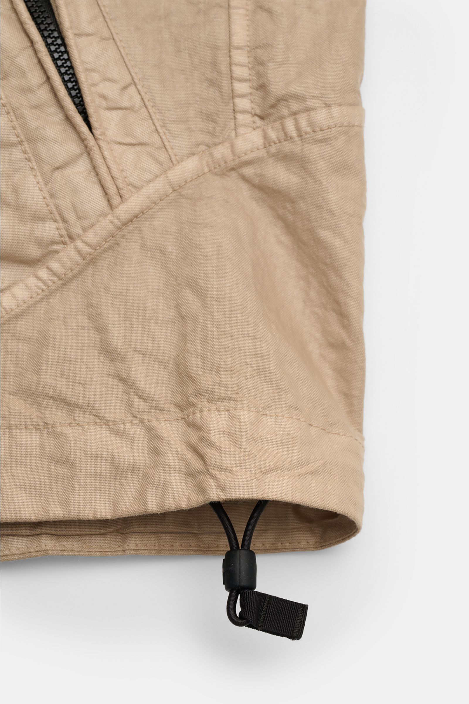 Close-up front view of the beige Stone Island Jacke 'Organic-Look Nylon Panama-TC' showing the fabric texture and adjustable hem cord.  
Mit der Jacke 'Organic-Look Nylon Panama-TC' präsentiert STONE ISLAND ein modernes Modell aus dicht gewebtem Microf