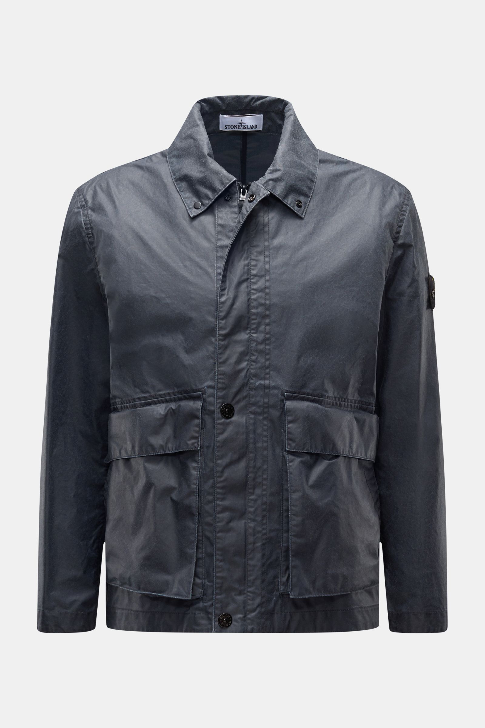 Front view of Stone Island Waxed jacket 'Waxed Pigment Cotton Tela' navy, featuring a waxed, water-repellent cotton-polyester canvas with adjustable collar and cuffs, robust two-way zip, storm flap, button flap pockets, and signature compass badge on the 
