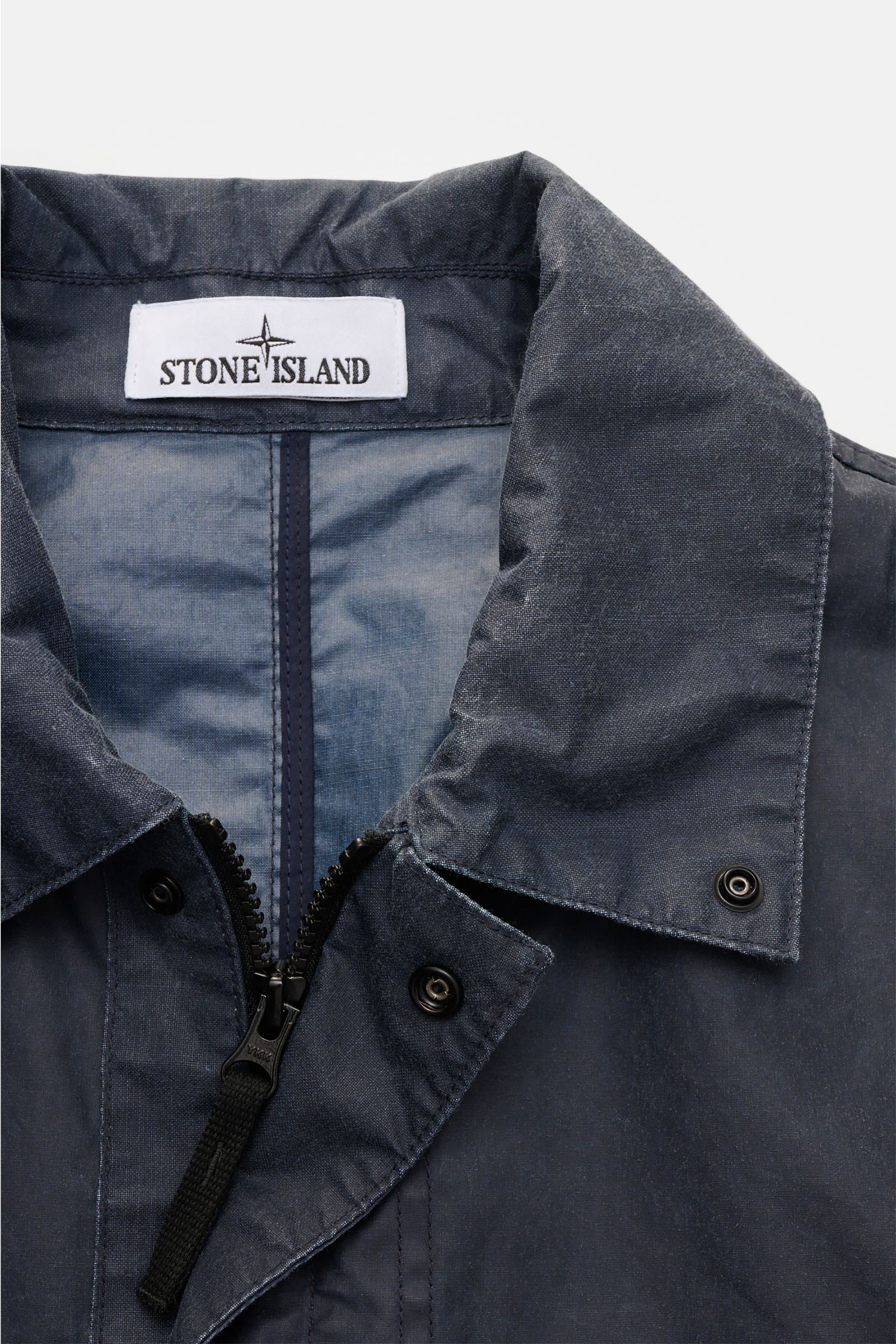 Stone Island Waxed jacket 'Waxed Pigment Cotton Tela' navy close-up front view showing collar, zipper, and snap buttons, made of waxed cotton blend.

The waxed jacket 'Waxed Pigment Cotton Tela' by STONE ISLAND features the expected level of innovation