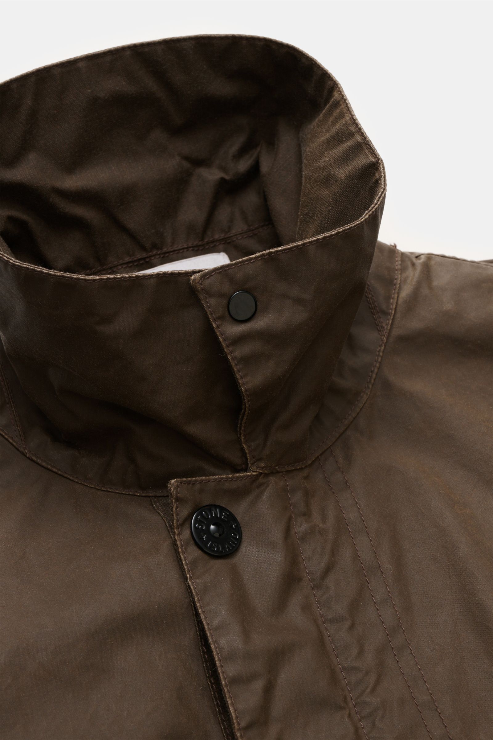 Stone Island Wachsjacke 'Waxed Pigment Cotton Tela' khaki im Nahaufnahme-Halsbereich, gewachster Baumwoll-Polyester-Canvas, wasserabweisend, variabler Kragen mit Druckknopf.