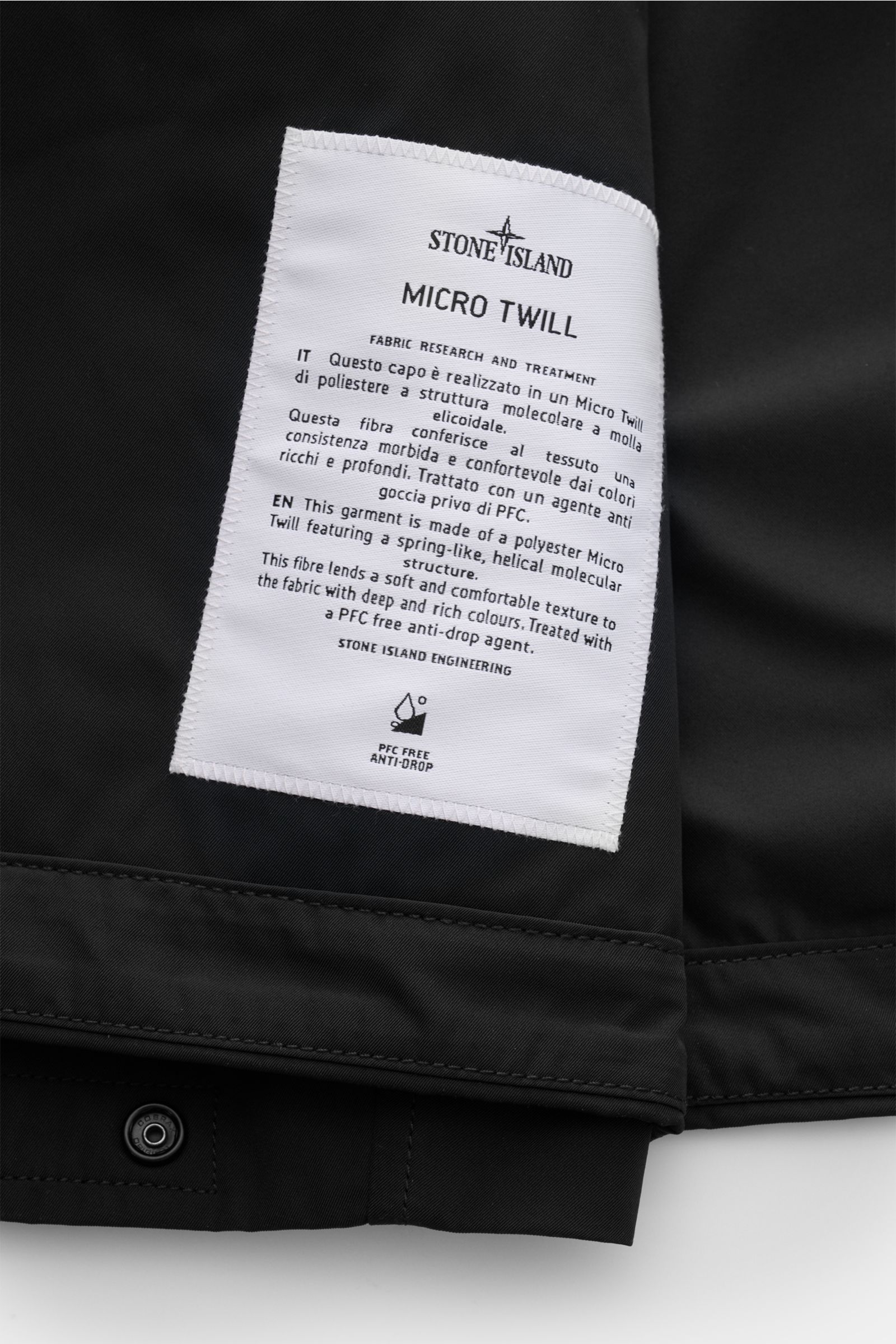 Close-up image of the inner label of the Stone Island Jacke 'Micro Twill' schwarz, showing fabric details and stitching. Eleganz trifft Funktion: Die STONE ISLAND Jacke überzeugt mit Micro-Twill in glatter, angenehmer Haptik und wird mit ihrer PFC-freien,