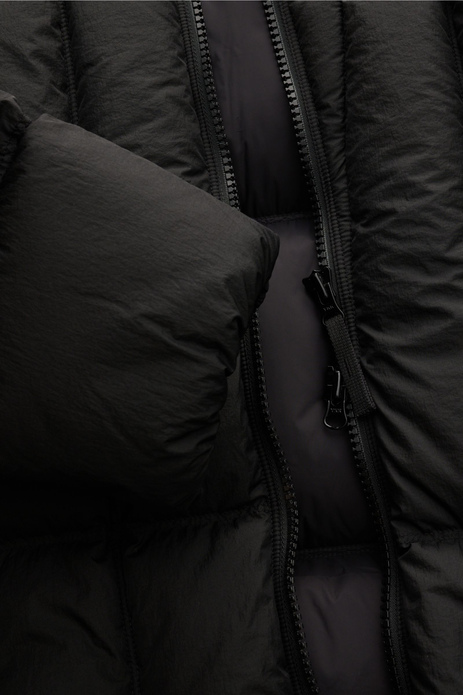 Close-up front view of the Stone Island Daunenjacke 'Seam Faded Light Nylon Tela' schwarz, showing the premium microfaser fabric, smooth texture, warm down filling, slim fit, two-way zipper, padded hood with drawstring, zipper front pockets, elastic cuffs
