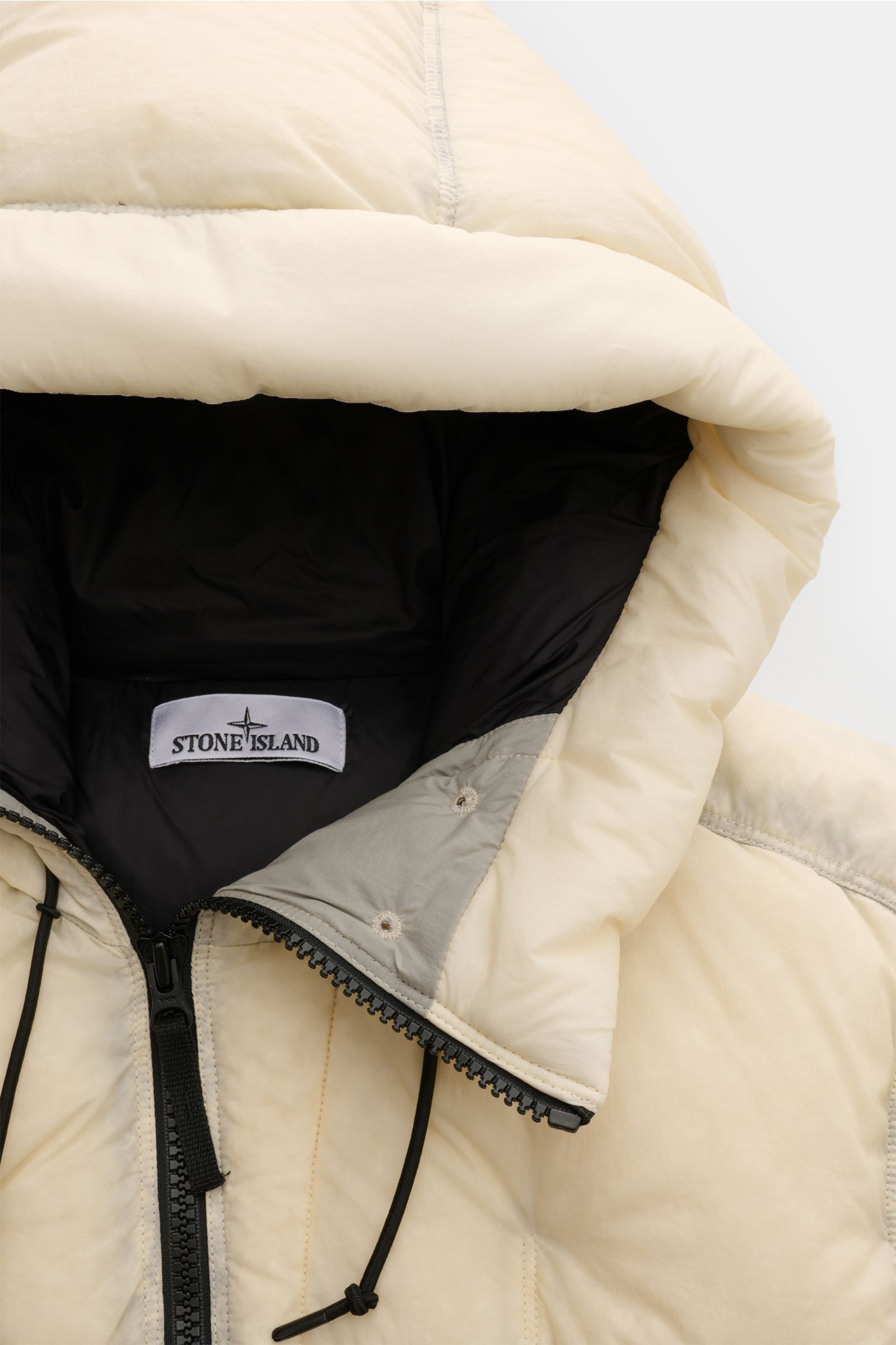 Alt-Tag (124 Zeichen): Nahaufnahme der Stone Island Daunenjacke 'Seam Faded Light Nylon Tela' offwhite mit Kapuze, Reißverschluss und wärmender Daunenfüllung.