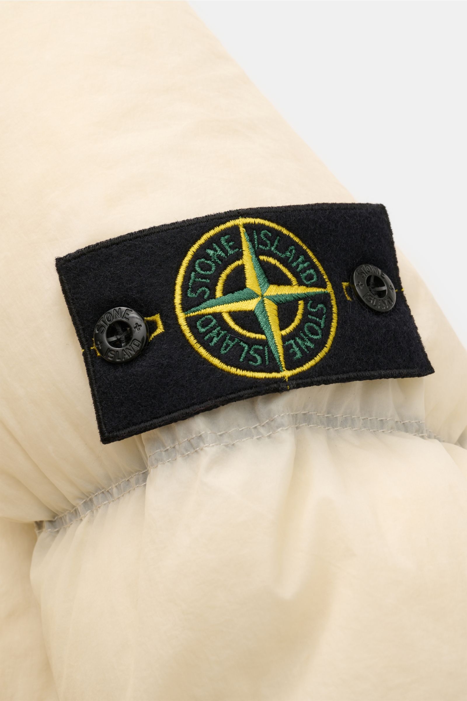Stone Island Daunenjacke 'Seam Faded Light Nylon Tela' offwhite, Detailansicht Ärmel mit Logo-Patch, wärmende Daunenfüllung, Microfaser.
