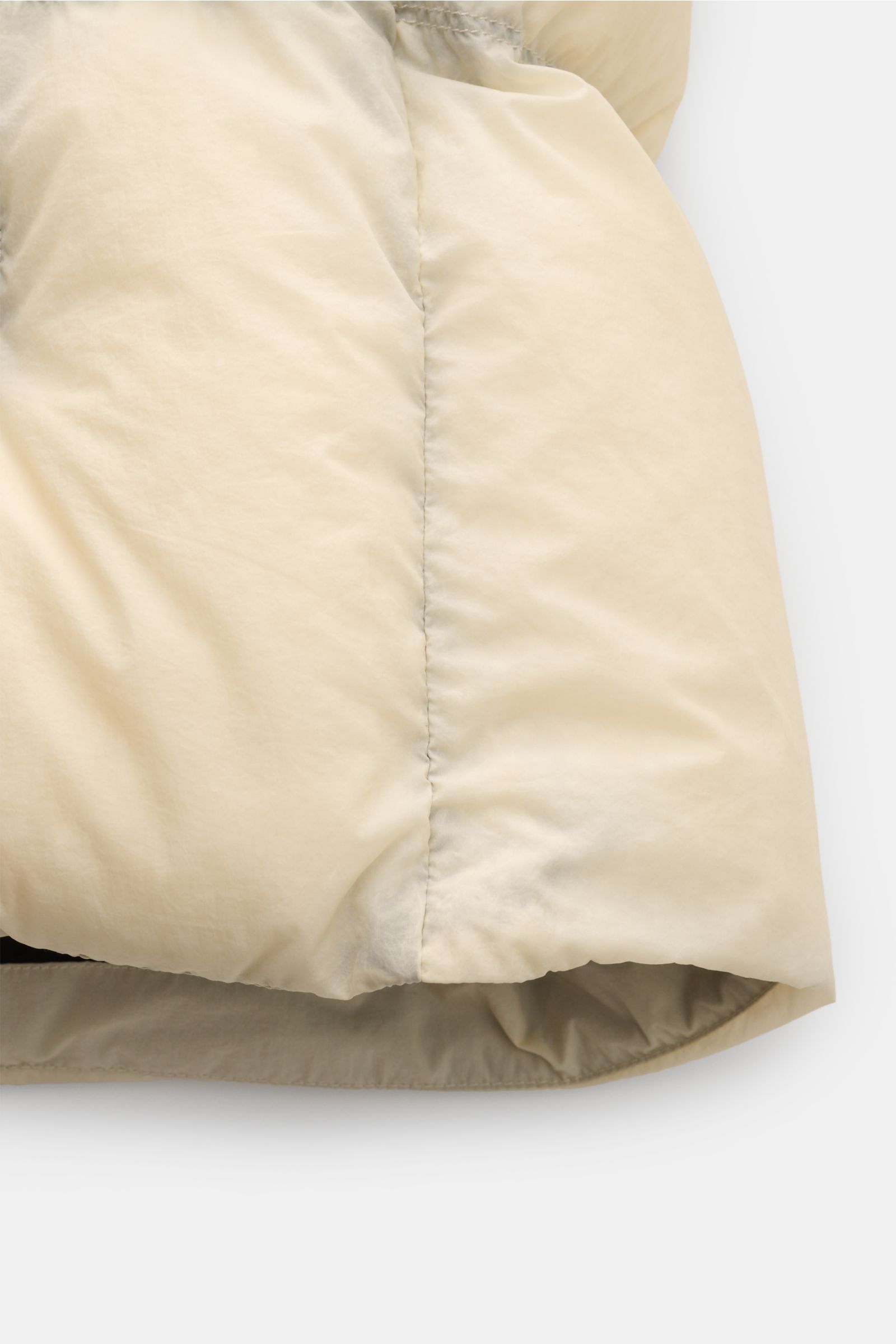 Stone Island Daunenjacke 'Seam Faded Light Nylon Tela' offwhite, Detailansicht vom Saum mit hochwertiger Microfaser und wärmender Daunenfüllung.