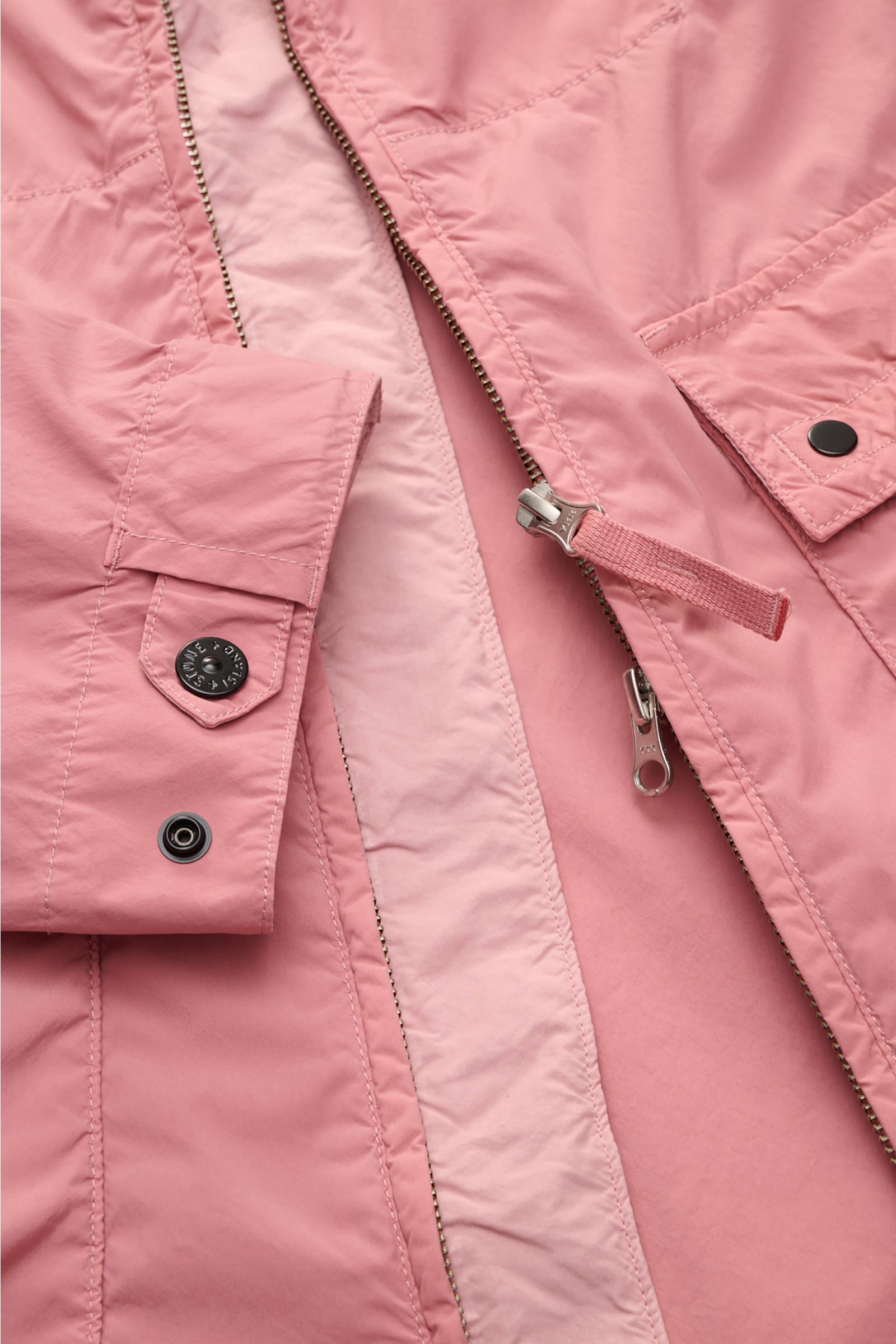 Close-up shot from above of the Stone Island Jacket 'Light Compact Touch Poly-TC' antique pink, showing the front zipper, snap-button cuffs, and flap pockets. Made for changeable days: The lightweight, water repellent jacket 'Light Compact Touch Poly-TC' 