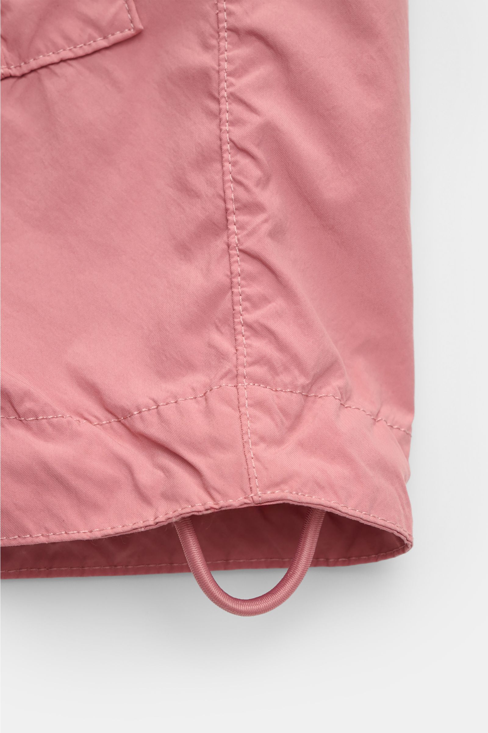 Close-up view of the hem and drawstring of the Stone Island Jacket 'Light Compact Touch Poly-TC' antique pink, made for changeable days, stretchy microfibre, water repellent, regular fit, with adjustable cuffs and signature compass badge.