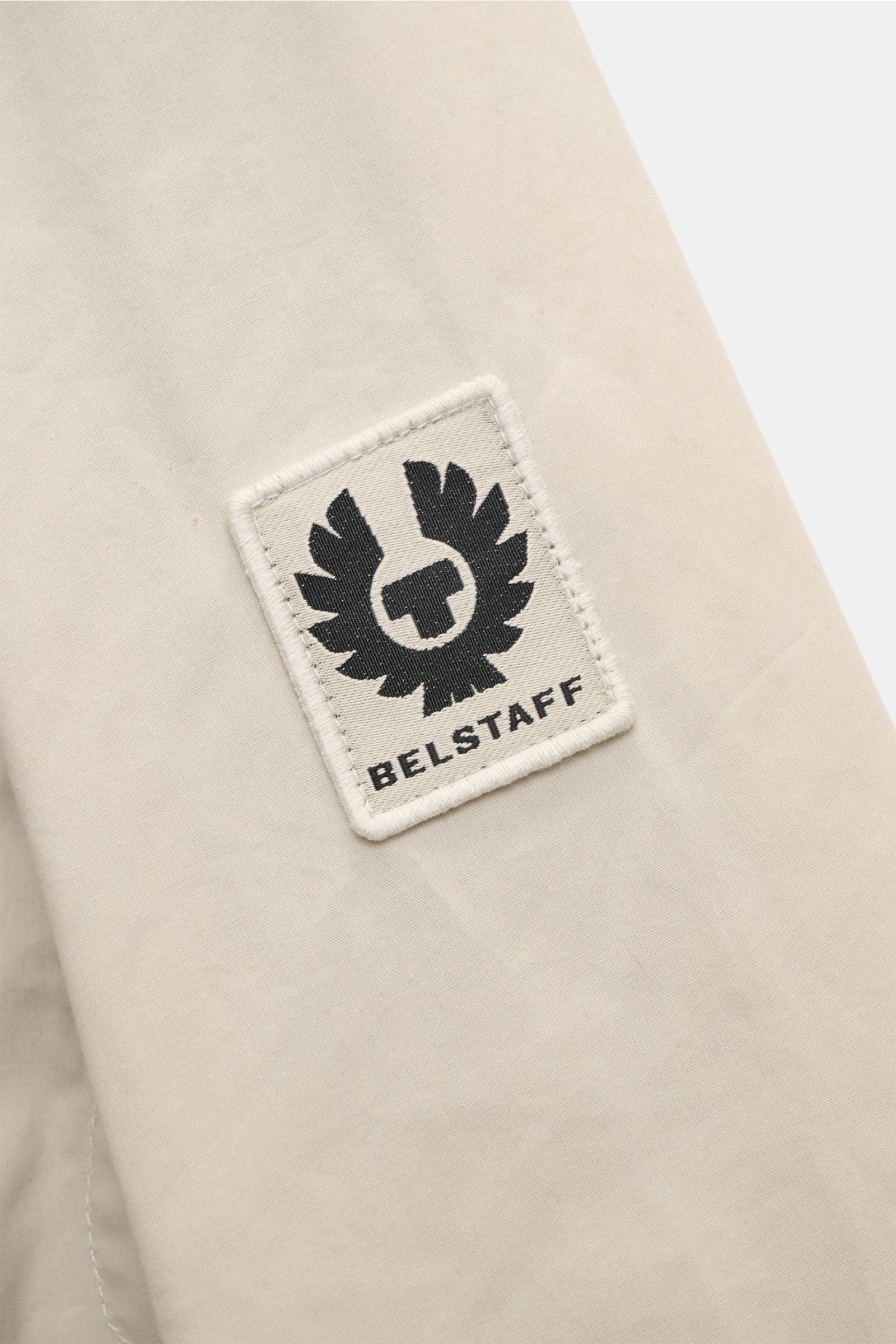 Close-up of the BELSTAFF woven label on the upper sleeve of the Belstaff Jacket 'Ground' cream/taupe, showing waxed cotton fabric texture from a side angle.

The classic from BELSTAFF: Made from waxed cotton in a boxy cut with a corduroy-trimmed collar