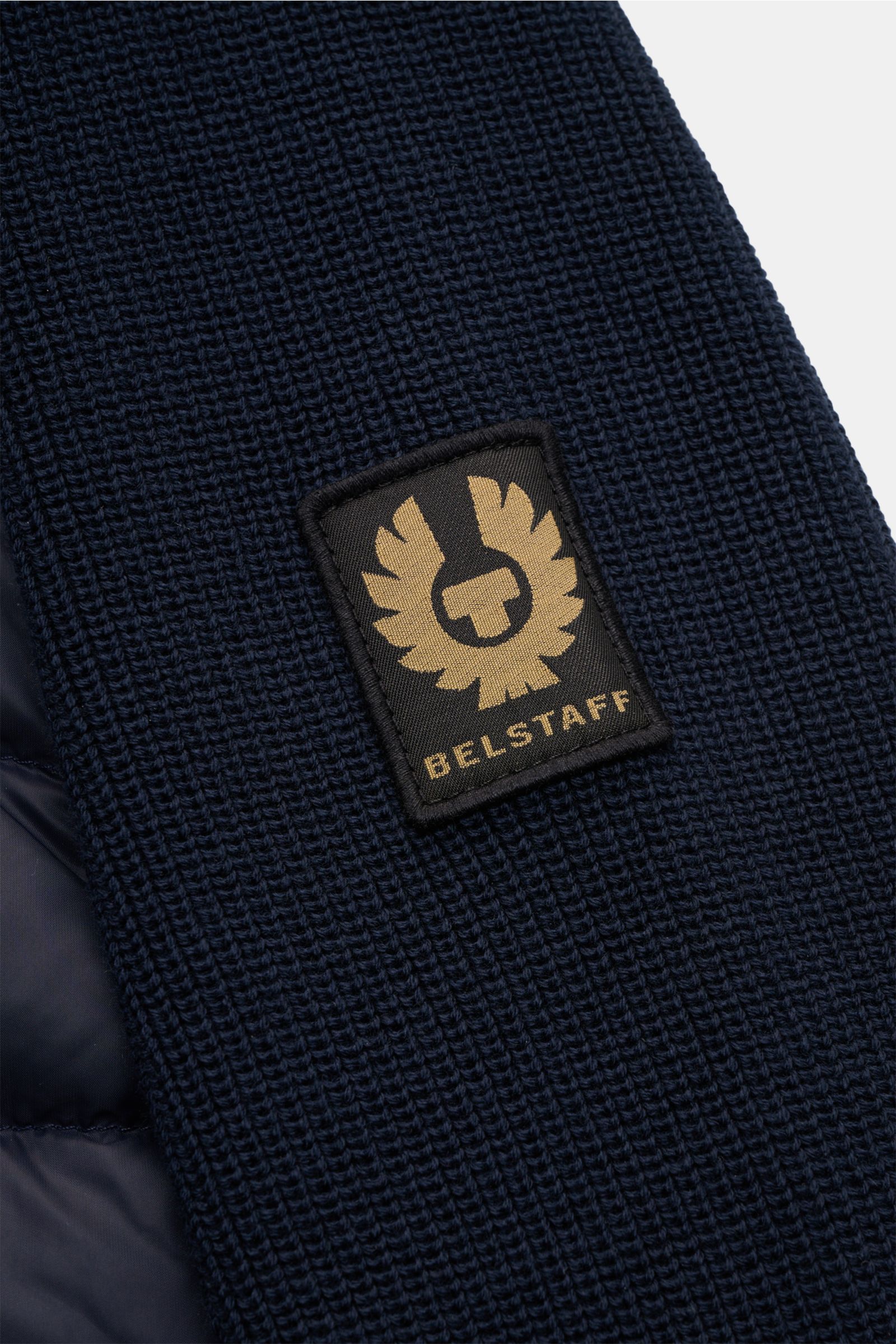 Close-up front-side view of the Belstaff Daunenjacke 'Control Cardigan' navy showing the navy wool knit sleeve with the BELSTAFF-Weblabel on the upper arm, featuring a microfiber front with quilted down filling, extra slim fit, two-way zipper, high stand-