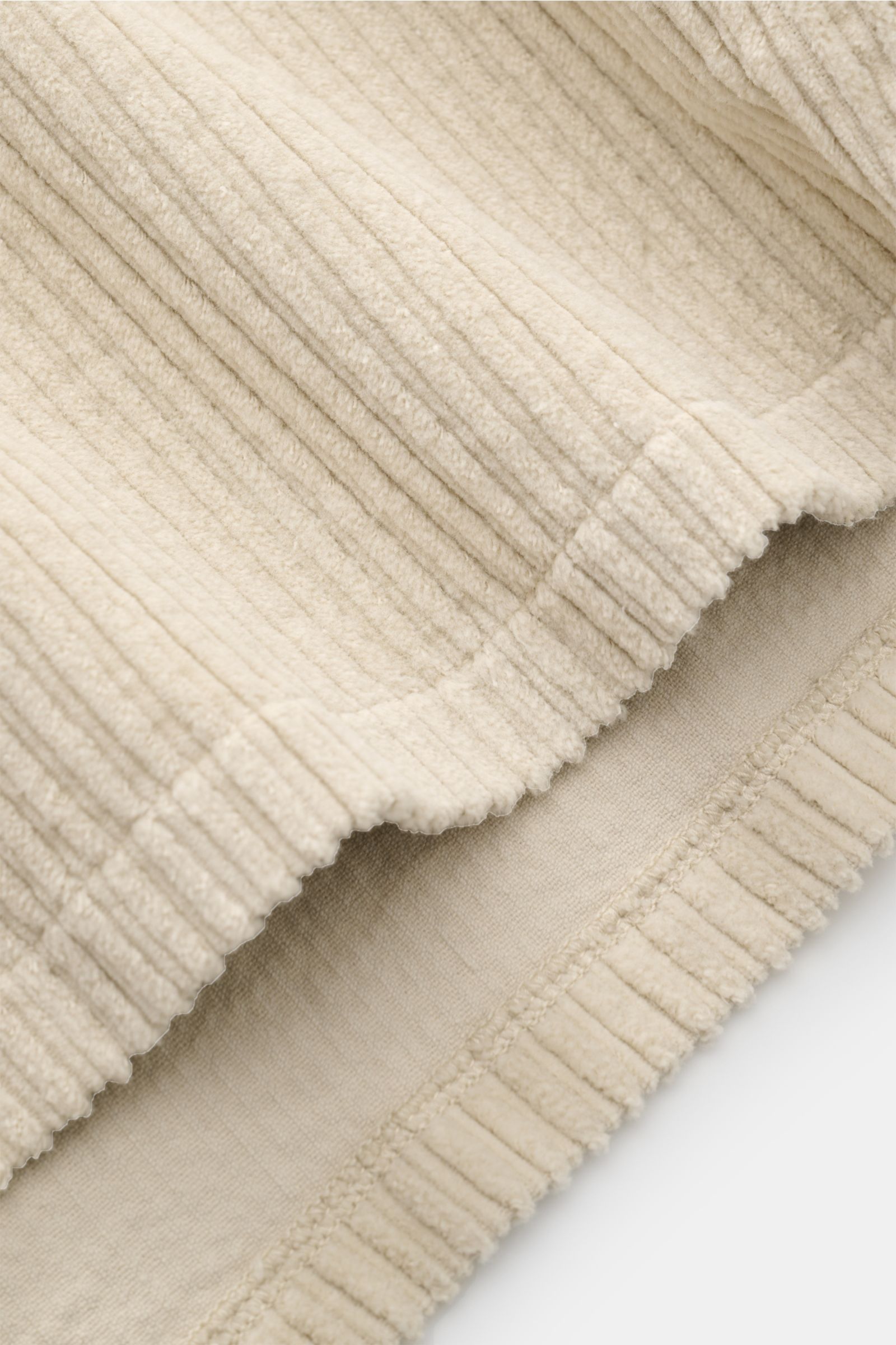 Nahaufnahme der leicht elastischen, sandfarbenen Baumwoll-Cord-Struktur des 04651/ A trip in a bag Cord-Overshirt sand, Detail der Kante aus schräger Perspektive.