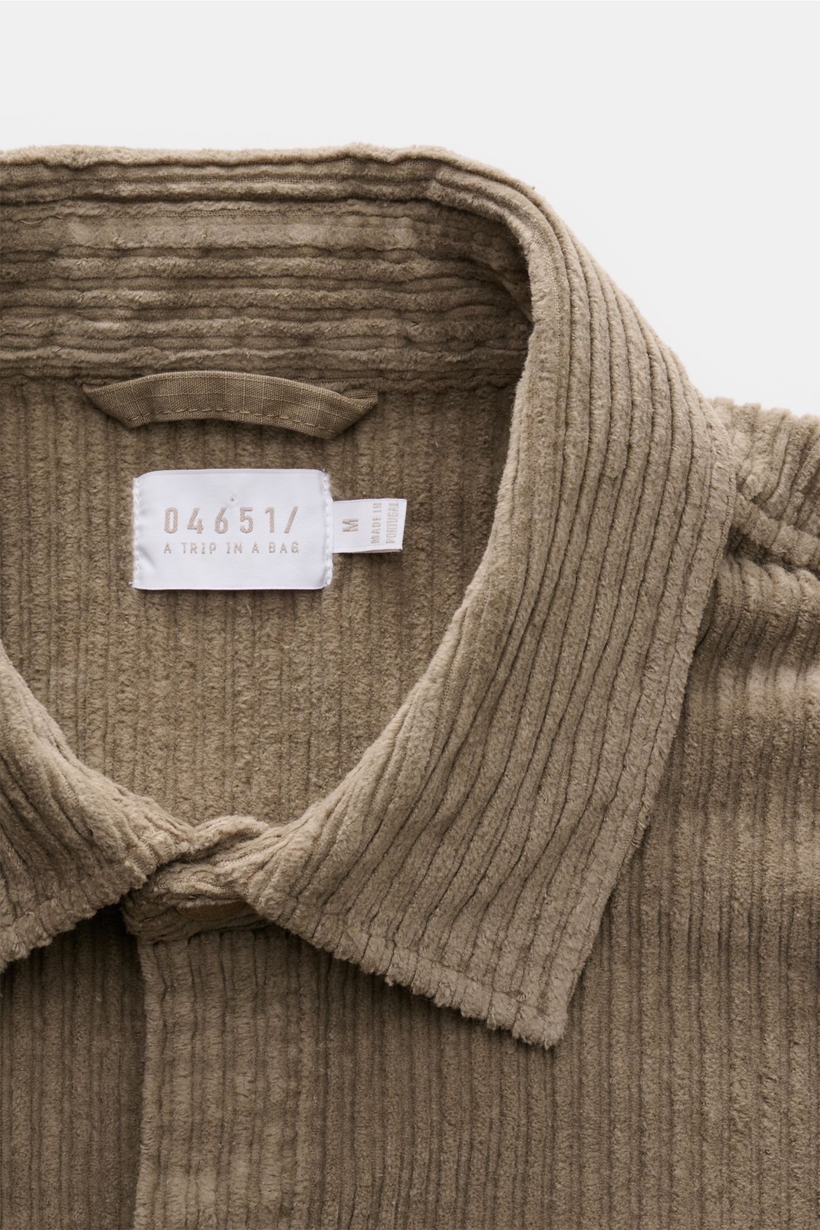 04651/ A trip in a bag Cord-Overshirt taupe, Nahaufnahme von Umlegekragen und Baumwoll-Cord mit leicht elastischer, materialtypischer Haptik.