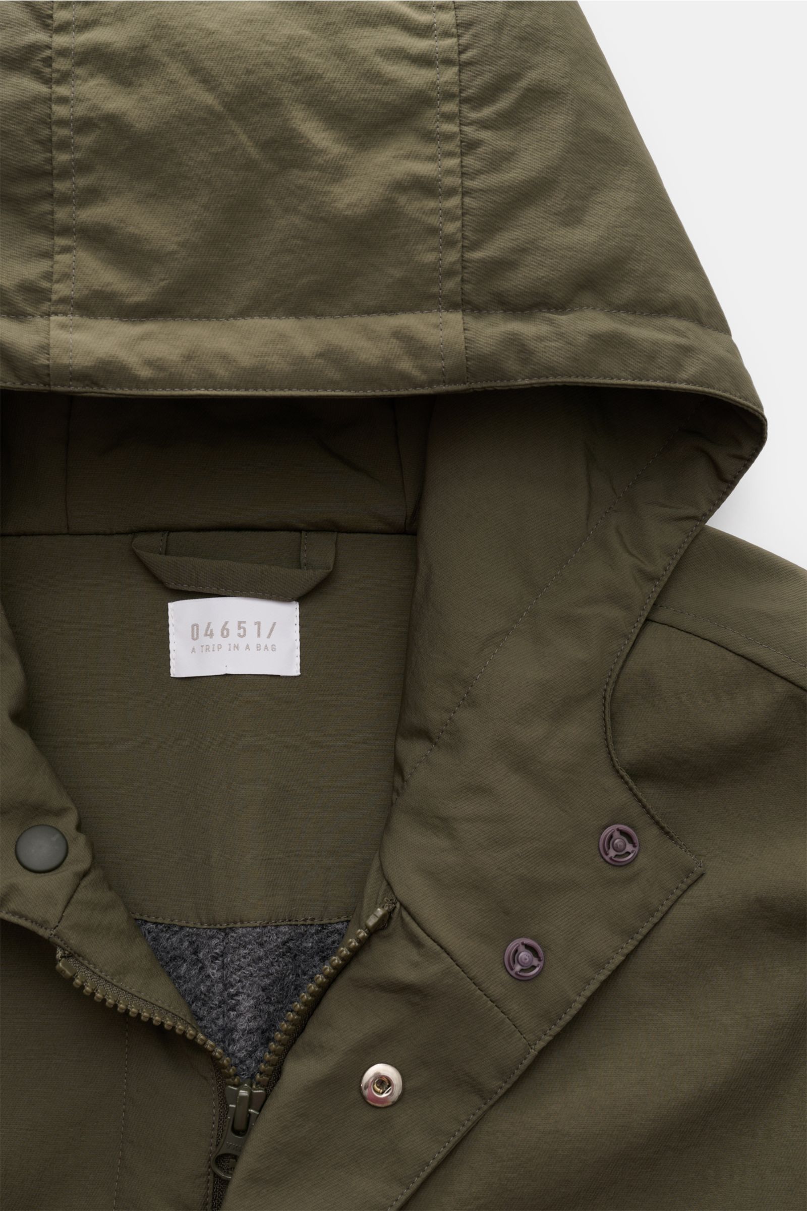Detailaufnahme von Kapuze und Kragen des olivfarbenen 04651/ A trip in a bag Parka 'The Coat' mit Reißverschluss, Knöpfen und hochwertiger Microfaser.