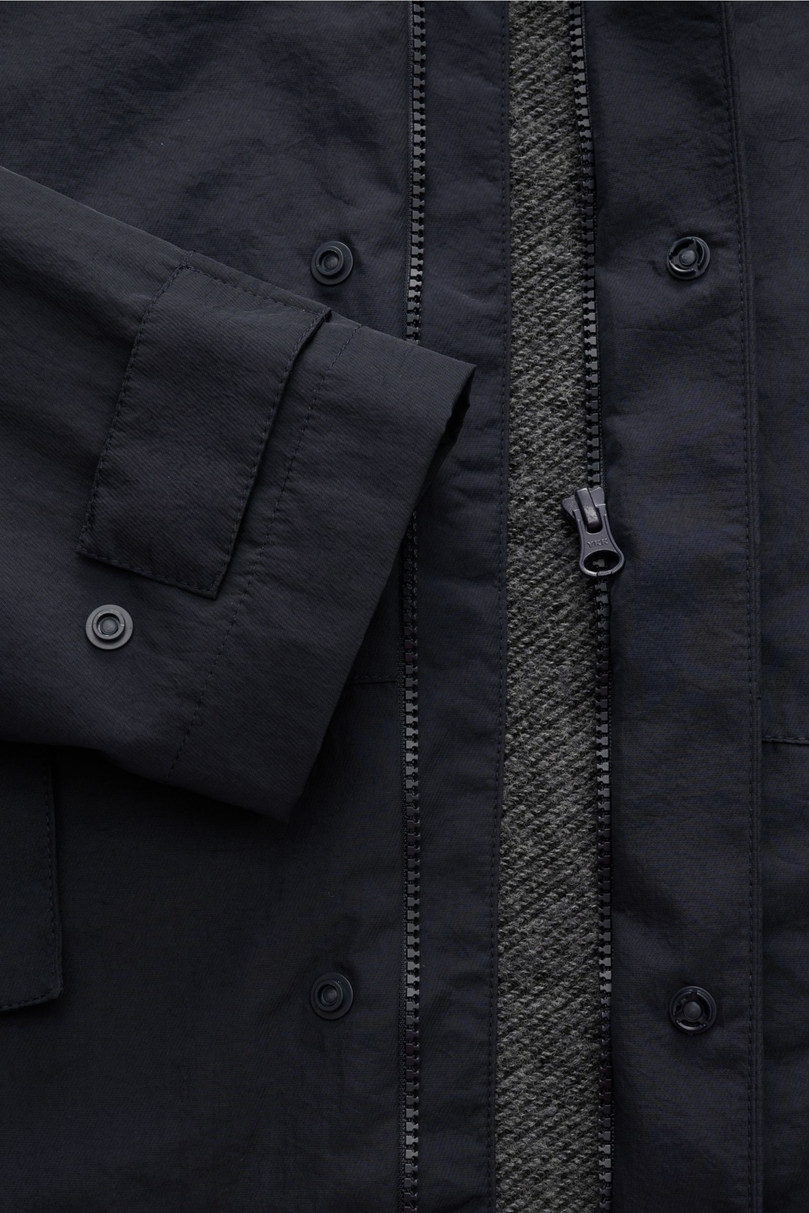 Close-up front view of the 04651/ A trip in a bag Jacket dark navy, showing high-quality microfibre, smooth feel, lightweight padding, wind and water repellent, regular fit, zip, concealed hood, raglan sleeves, hip pockets with flap, woven label, snap but