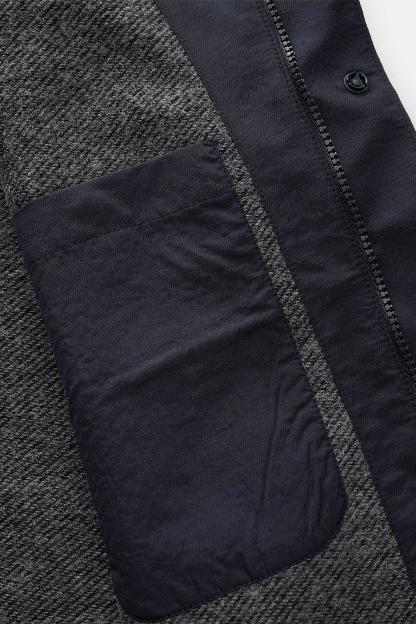 Close-up interior view of the 04651/ A trip in a bag Jacket dark navy showing high-quality microfibre lining with smooth feel, lightweight padding, zip, concealed hood in the collar, raglan sleeves, hip pockets with flap, small woven label in the side sea