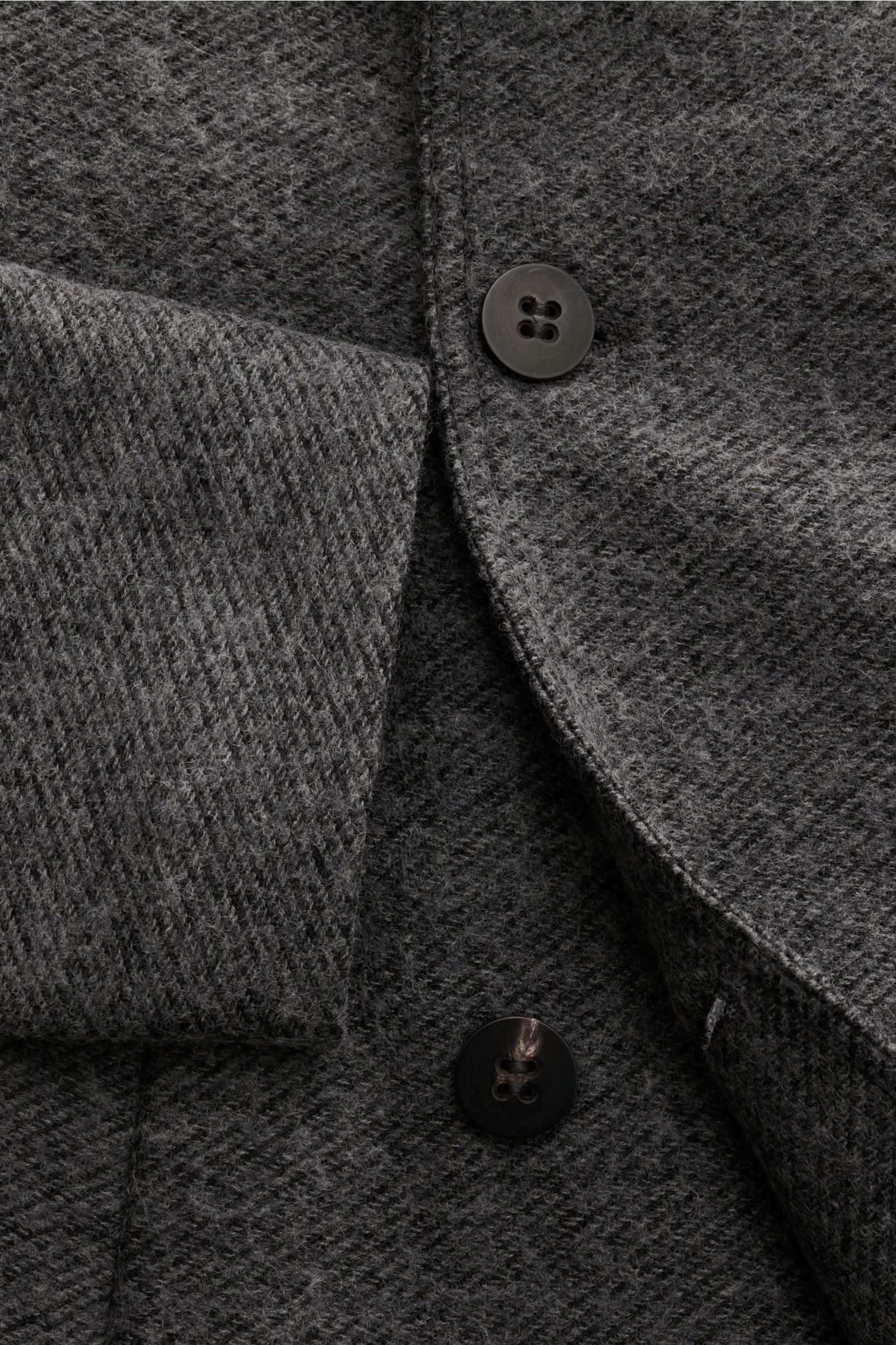 Nahaufnahme der 04651/ A trip in a bag Cabanjacke dunkelgrau meliert aus schräger Perspektive, Mix aus Wolle und Microfaser, Slim Fit, zweireihige Drei-Knopf-Leiste, variabler Reverskragen, schräge Leistentaschen, glatter Futterstoff, eine Innentasche, le