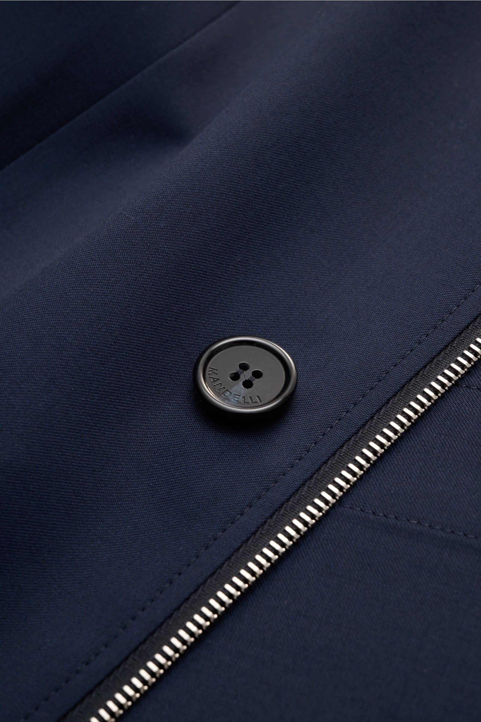 Nahaufnahme der Mandelli Jacke navy aus reiner Schurwolle mit glattem Griff, Knopf mit Prägung und zwei-Wege-Reißverschluss.