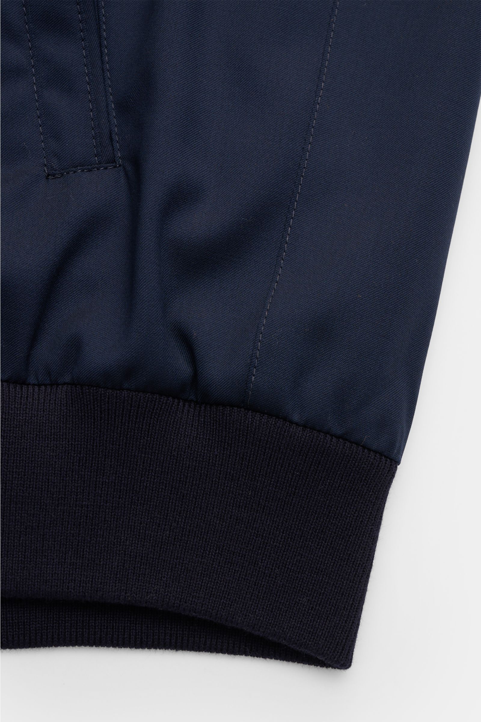 Close-up of the hem and sleeve cuff of the Mandelli Blouson navy, photographed from a front angle, showing pure wool fabric, smooth feel, slim fit, elastic hem and sleeve cuffs. Elegant ease for the transitional period: This blouson by MANDELLI combines l