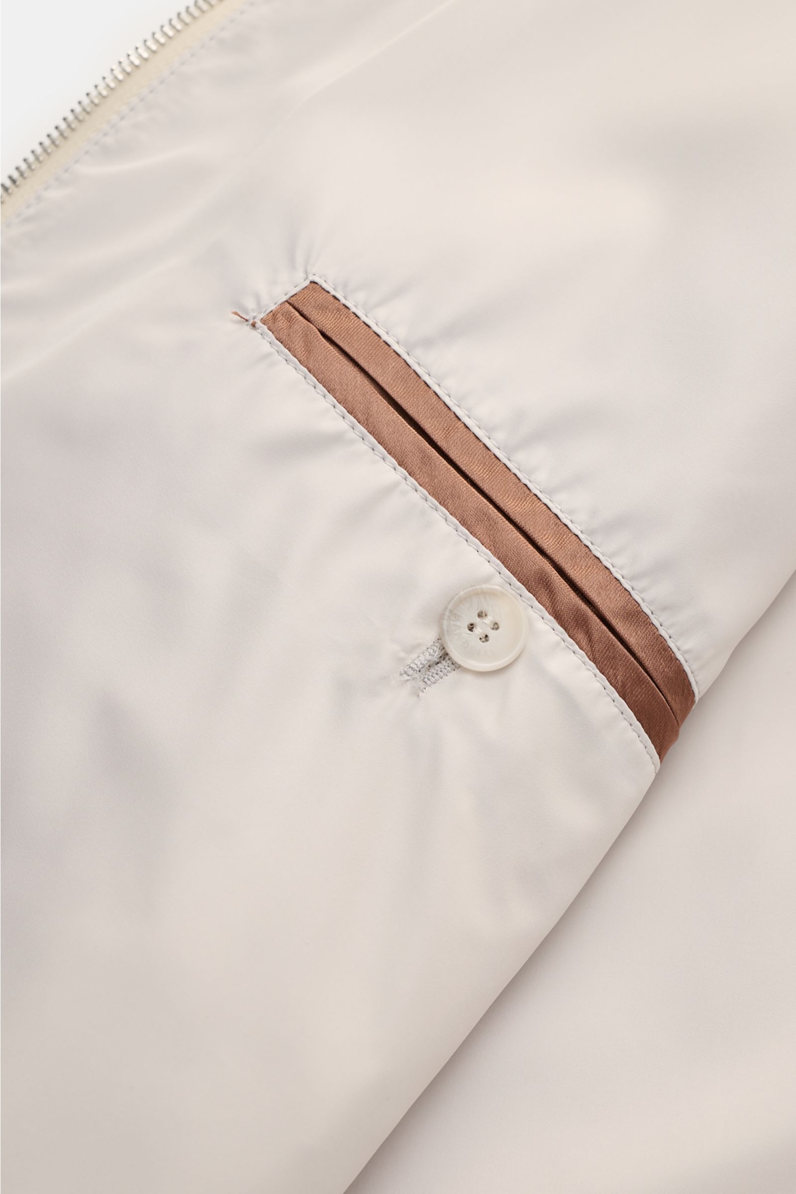 Nahaufnahme des Innenfutters vom Mandelli Blouson beige mit glattem Griff, drei Innentaschen und Knopfverschluss, seitlich fotografiert.